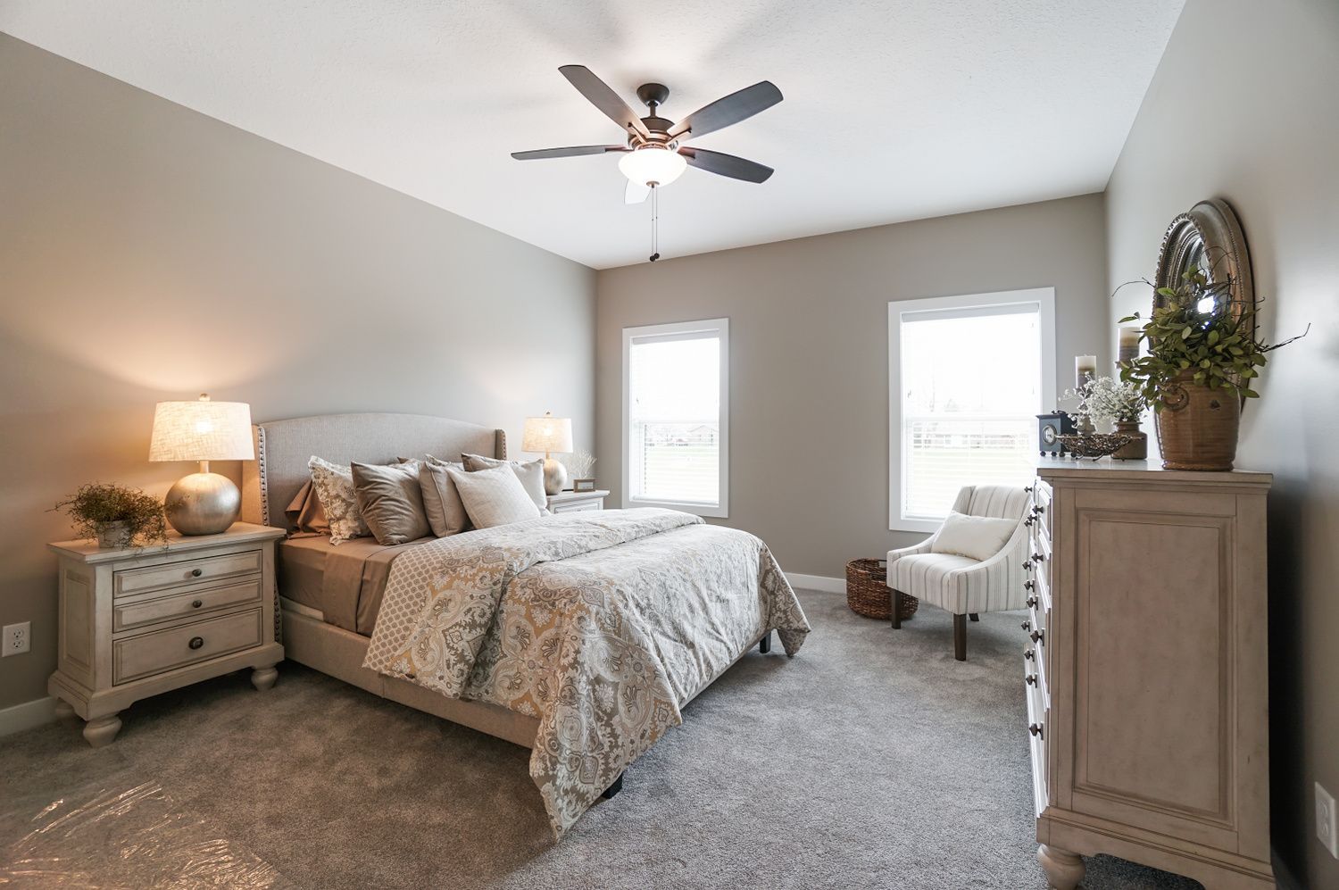 A bedroom with a bed , dresser , nightstand , chair and ceiling fan.