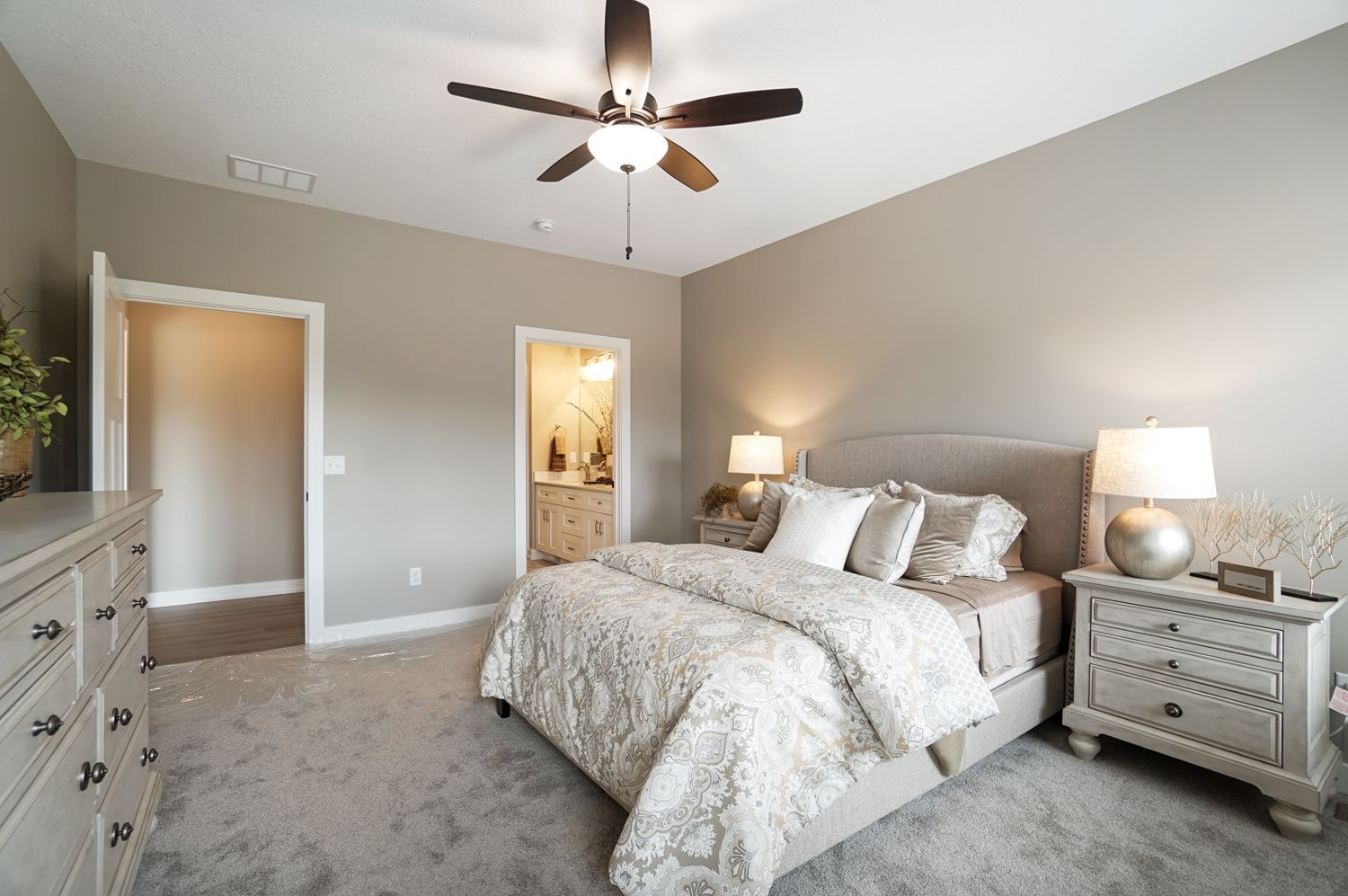 A bedroom with a bed , nightstand , dresser and ceiling fan.