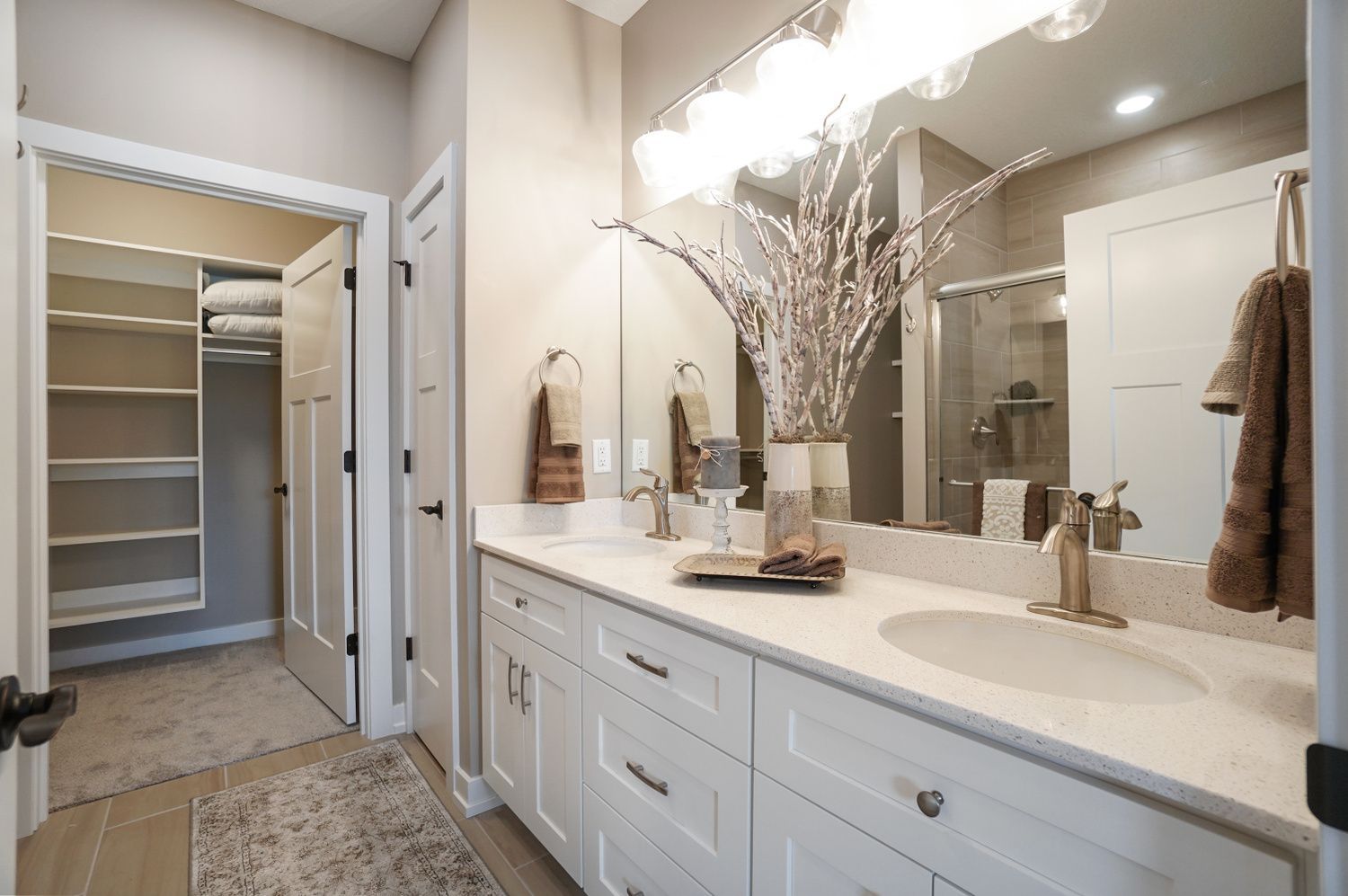 A bathroom with two sinks , a large mirror and a walk in closet.