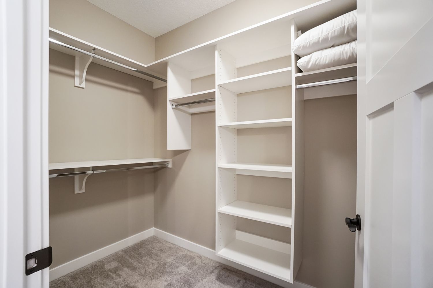 A walk in closet with lots of shelves and a door.