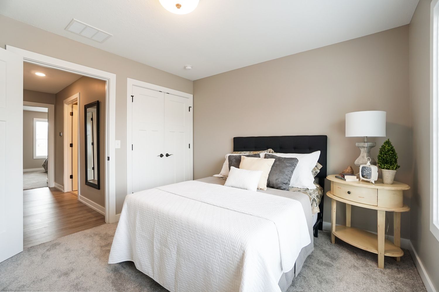 A bedroom with a bed , nightstand , lamp and closet.