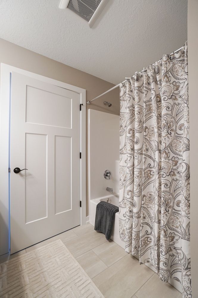 A bathroom with a shower curtain and a bathtub.
