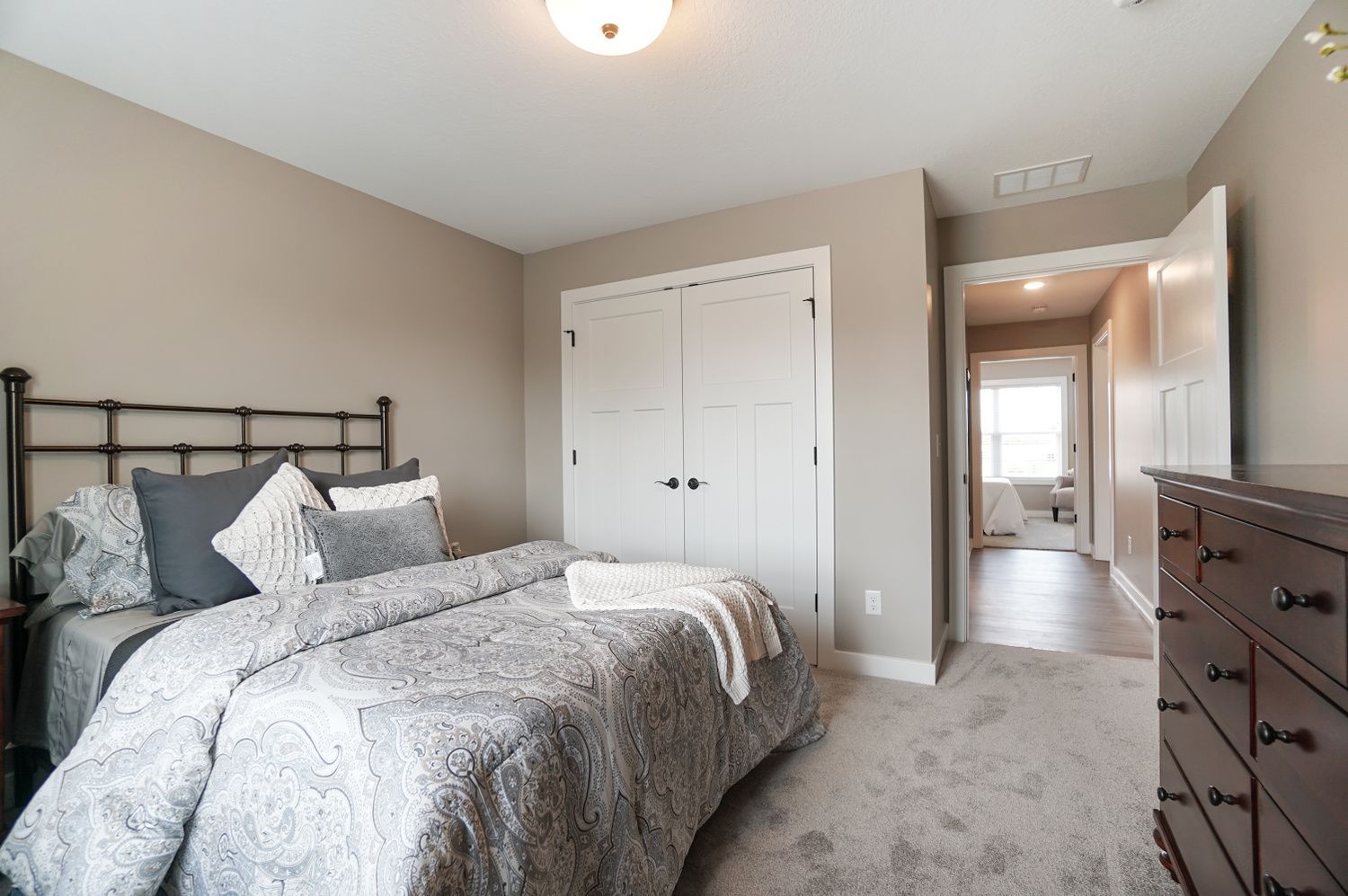 A bedroom with a bed , dresser , nightstand and closet.