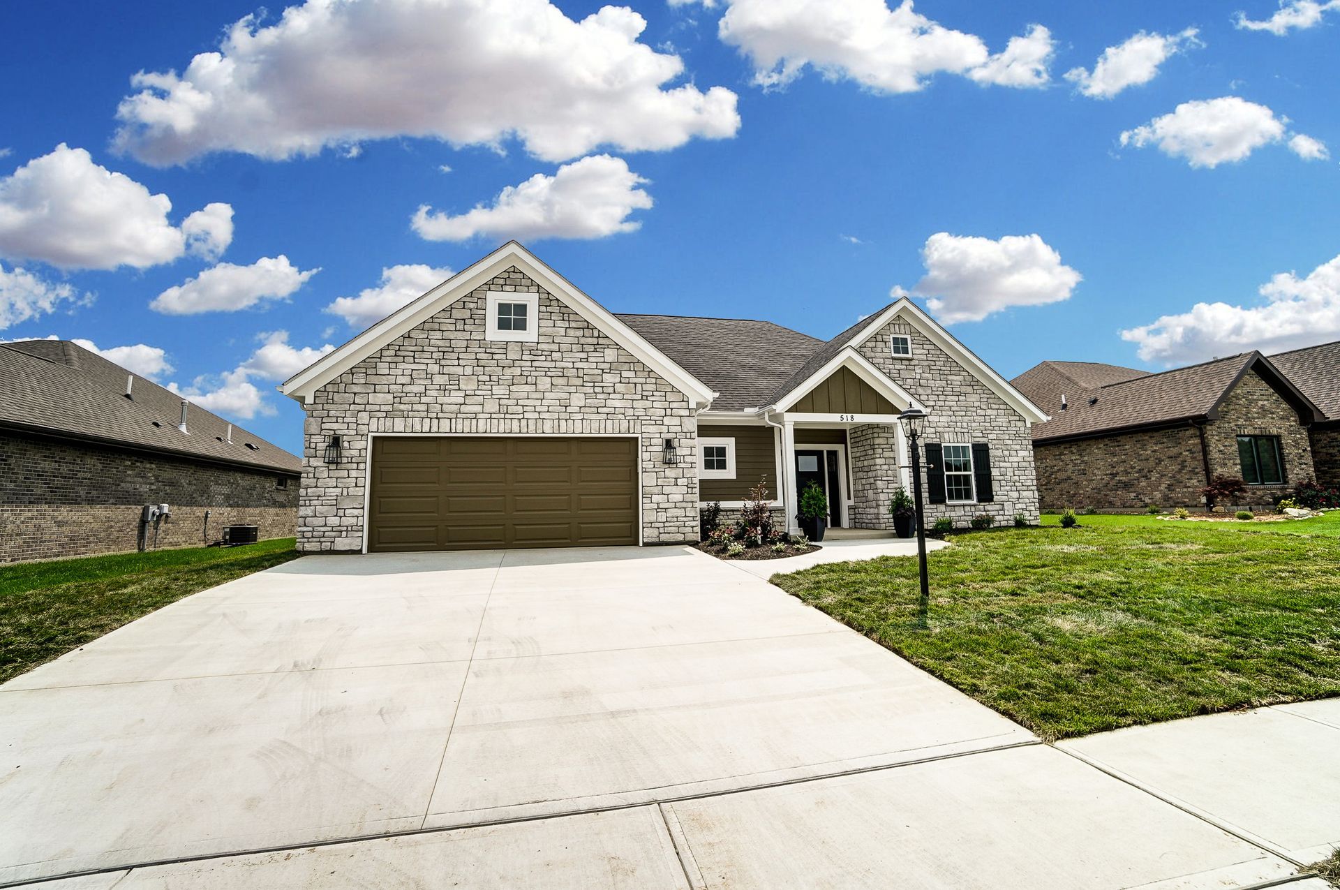 A large stone house with a large garage and a concrete driveway.