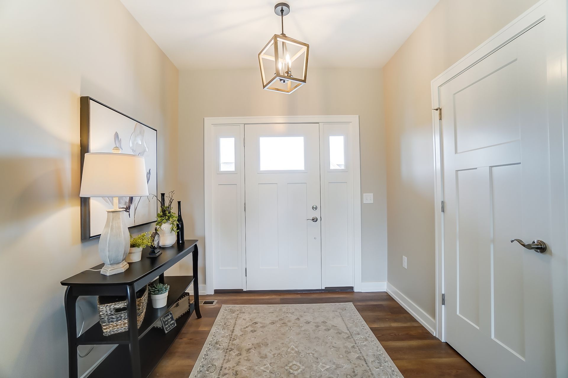 A hallway with a table and lamps in front of a door.