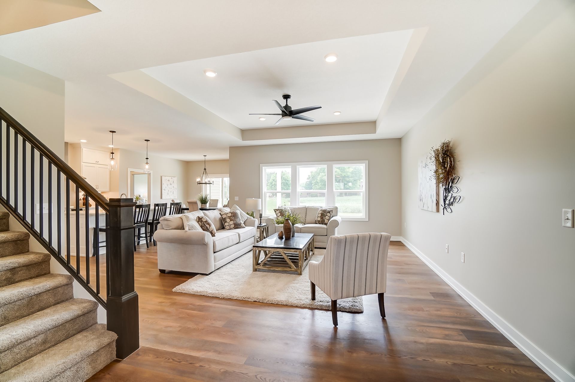 A living room with a staircase leading up to it and a ceiling fan.