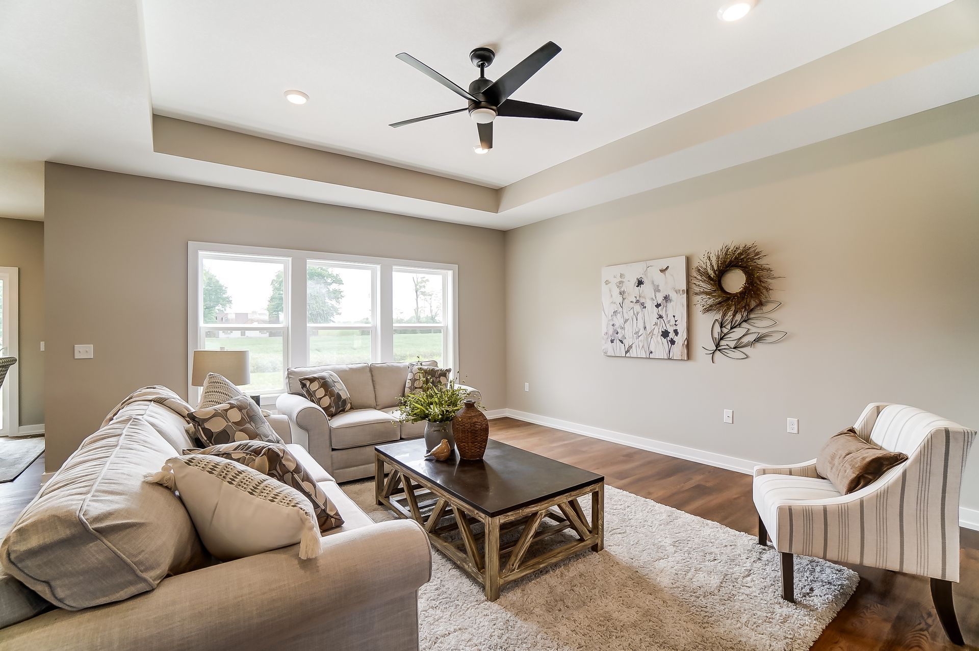 A living room with a couch , chair , coffee table and ceiling fan.