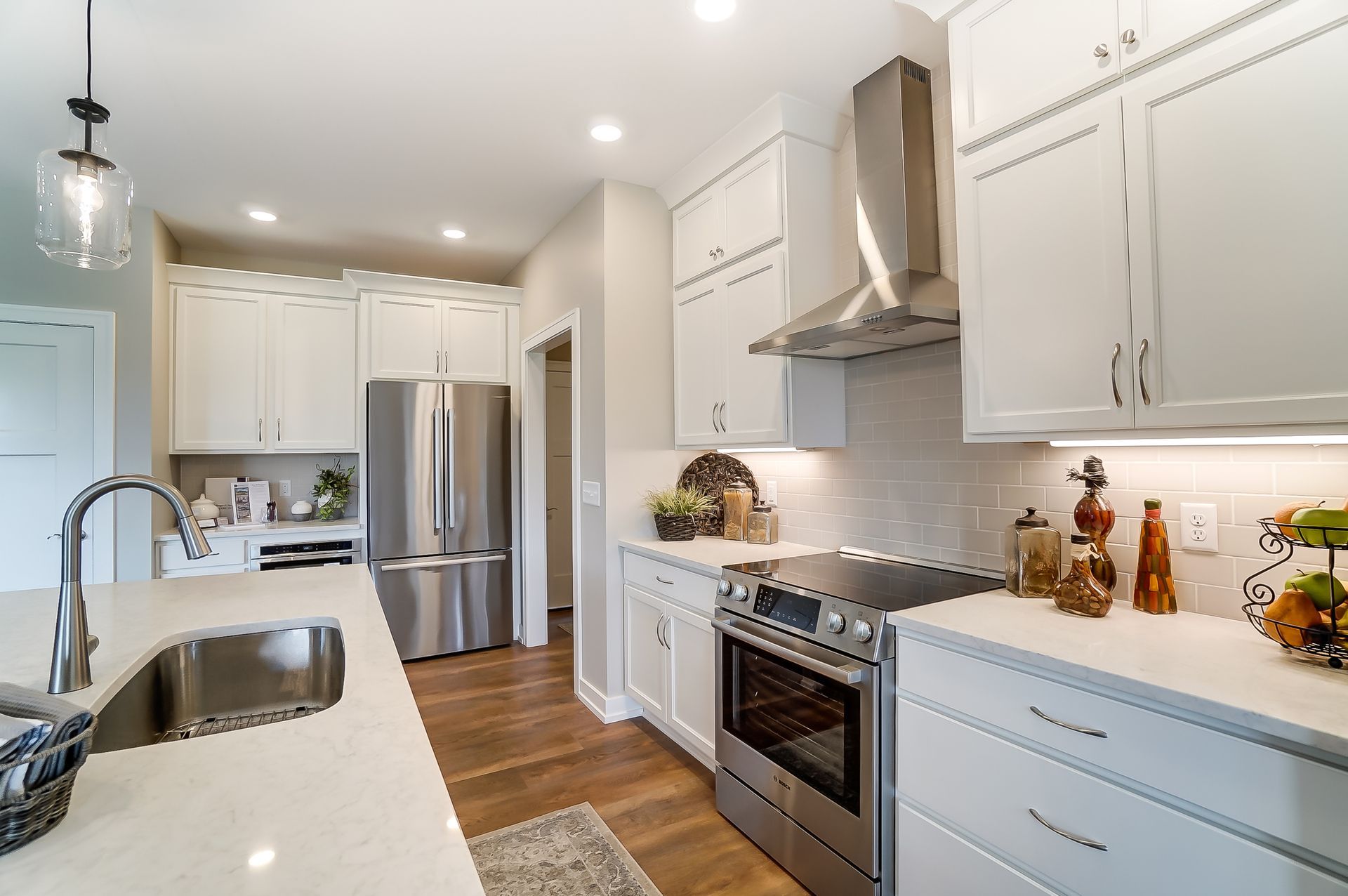 A kitchen with white cabinets , stainless steel appliances , a sink , and a refrigerator.