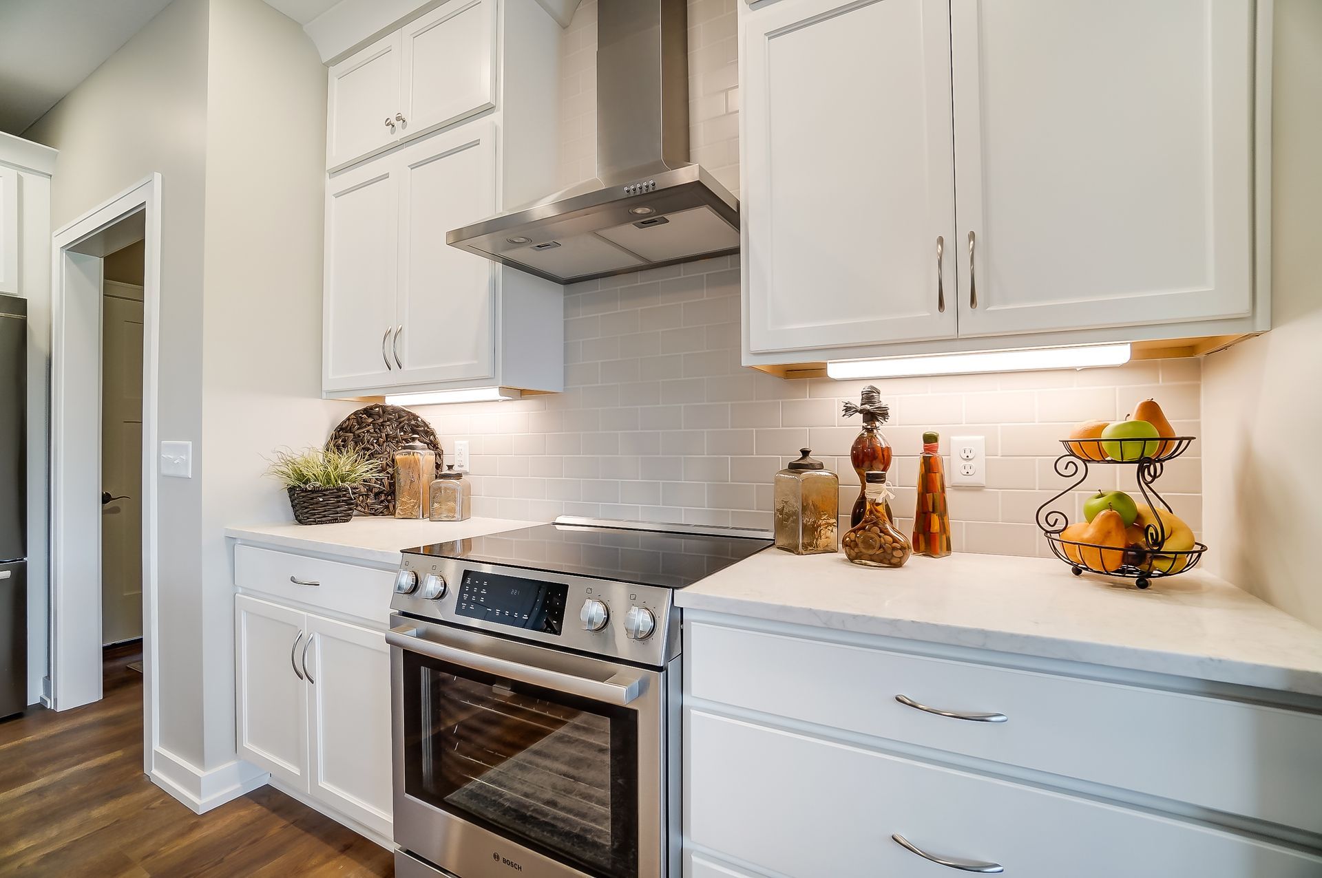 A kitchen with white cabinets , stainless steel appliances , and a stove.