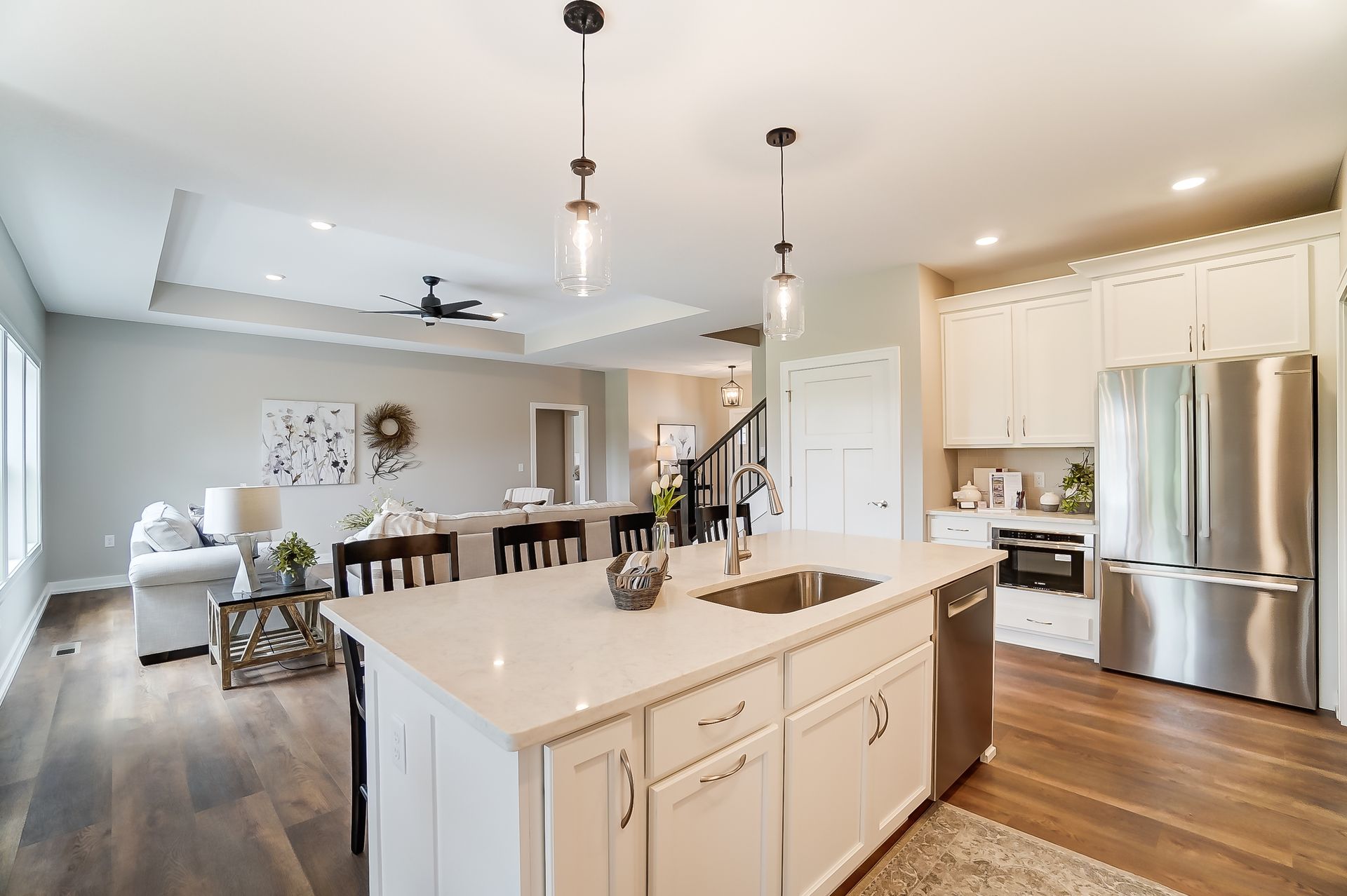A kitchen with white cabinets and stainless steel appliances and a large island in the middle.