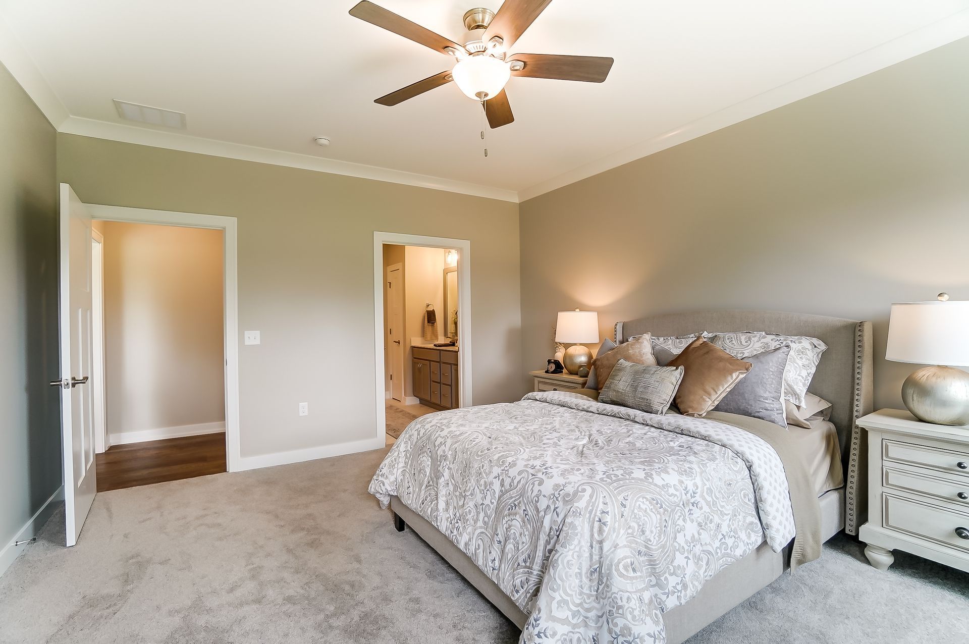 A bedroom with a bed , nightstand , lamp and ceiling fan.