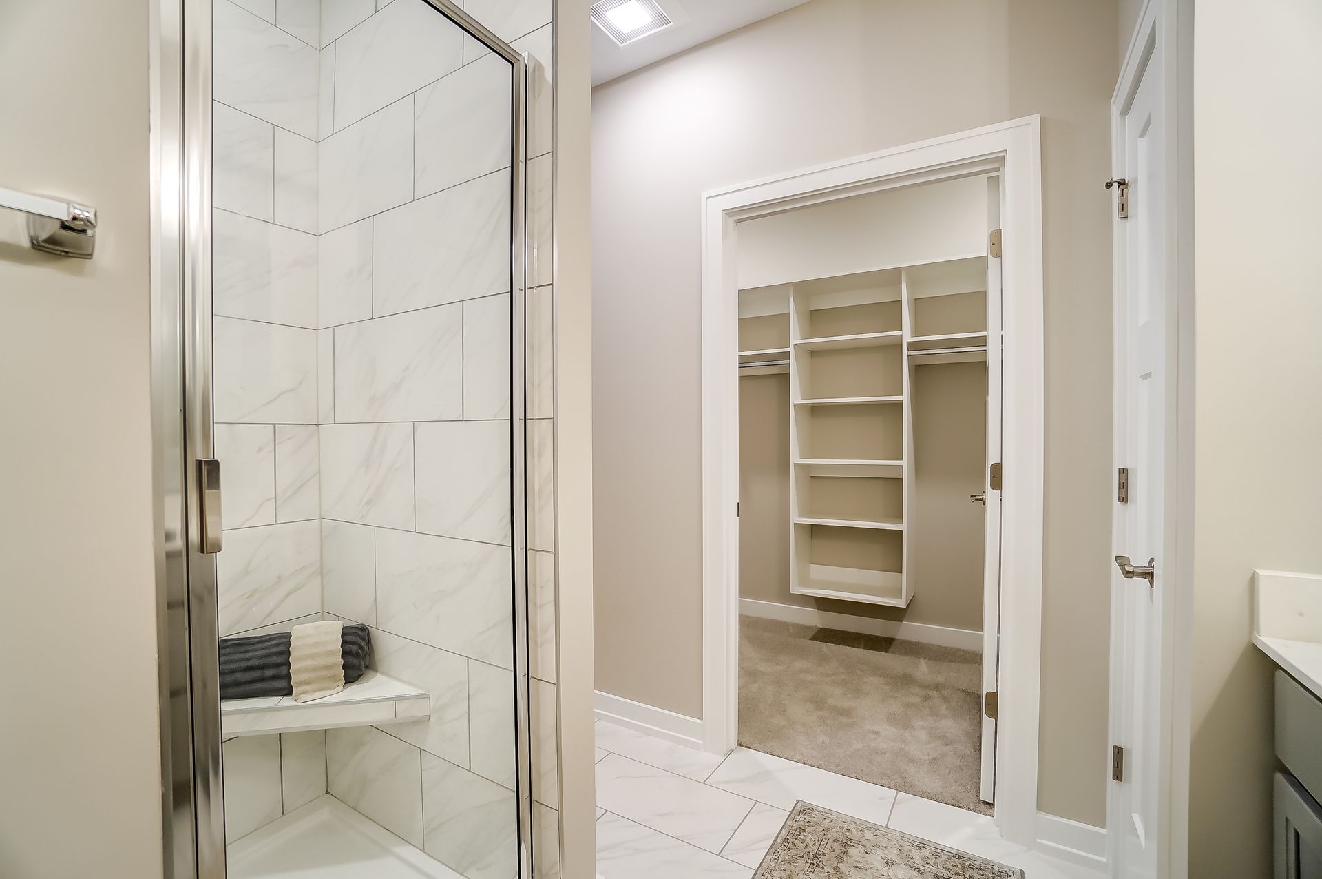 A bathroom with a walk in closet and a shower.