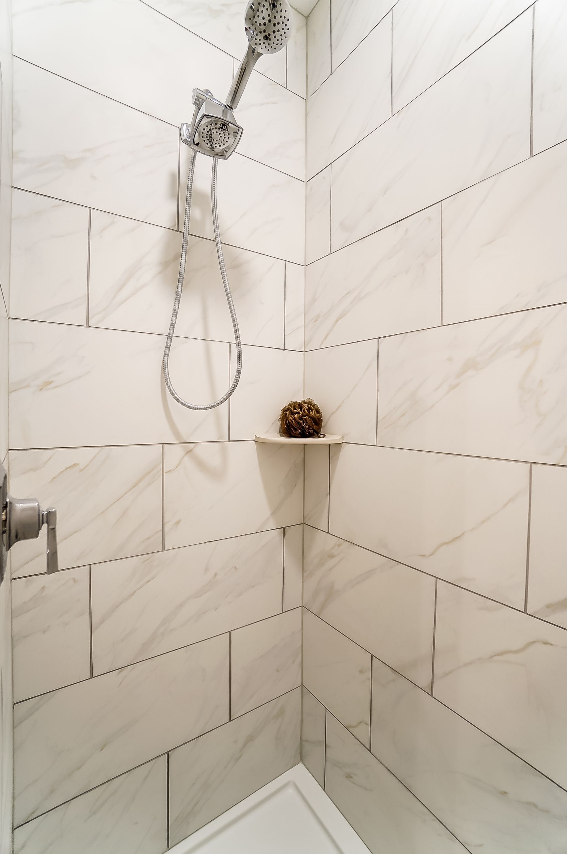 A shower with white tiles and a shower head on the wall.