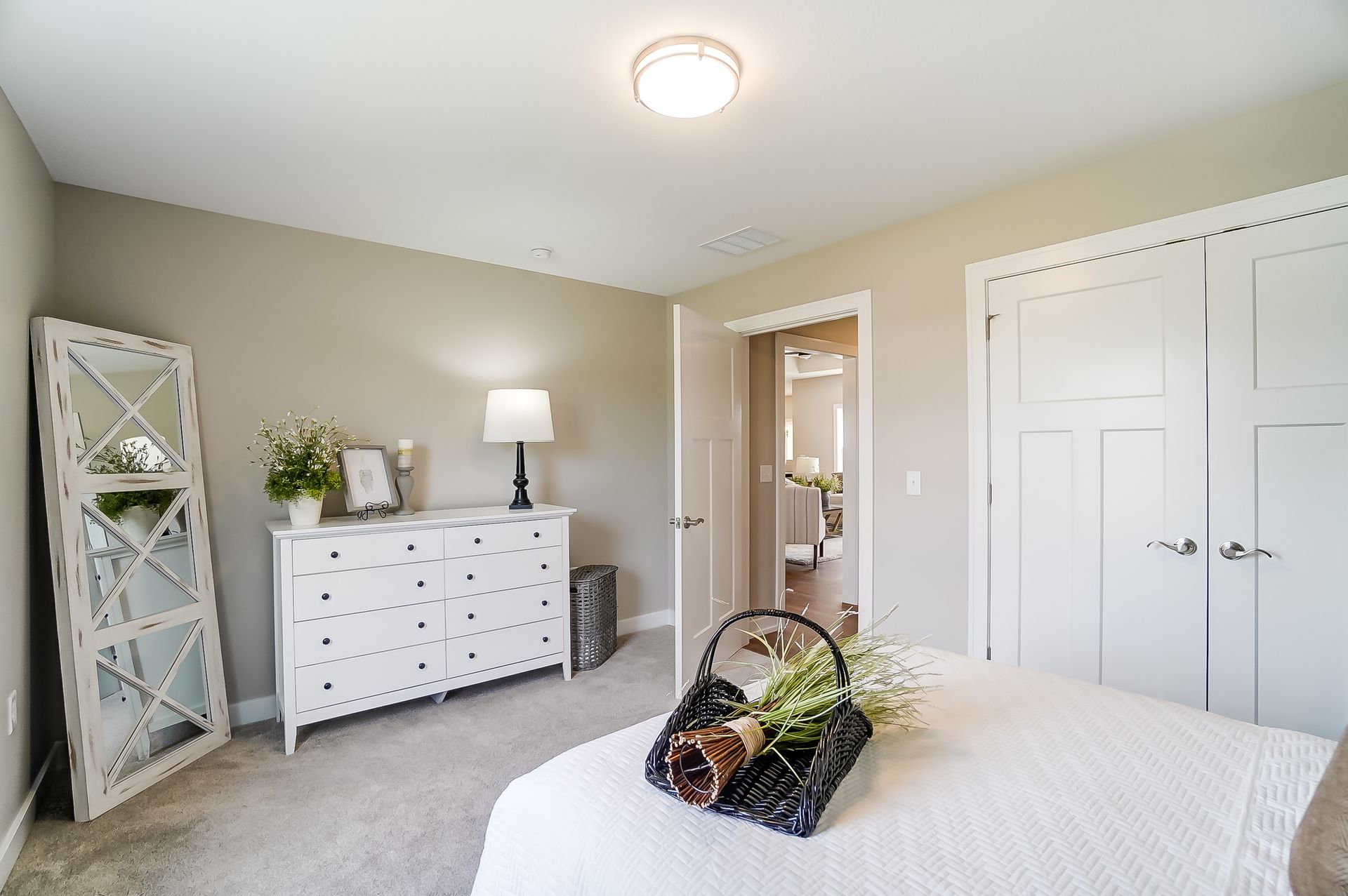 A bedroom with a bed , dresser , mirror and lamp.