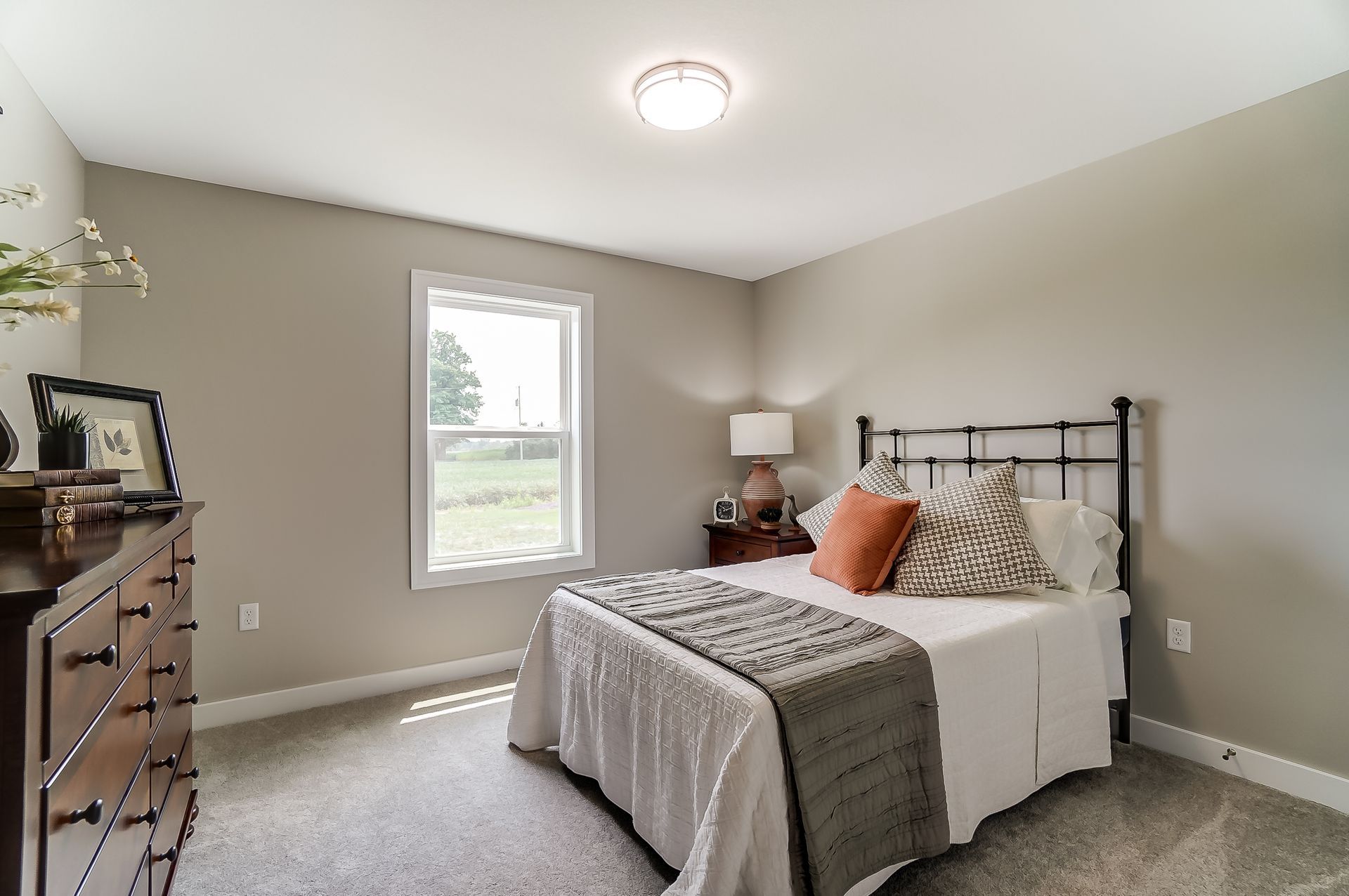 A bedroom with a bed , dresser , and window.