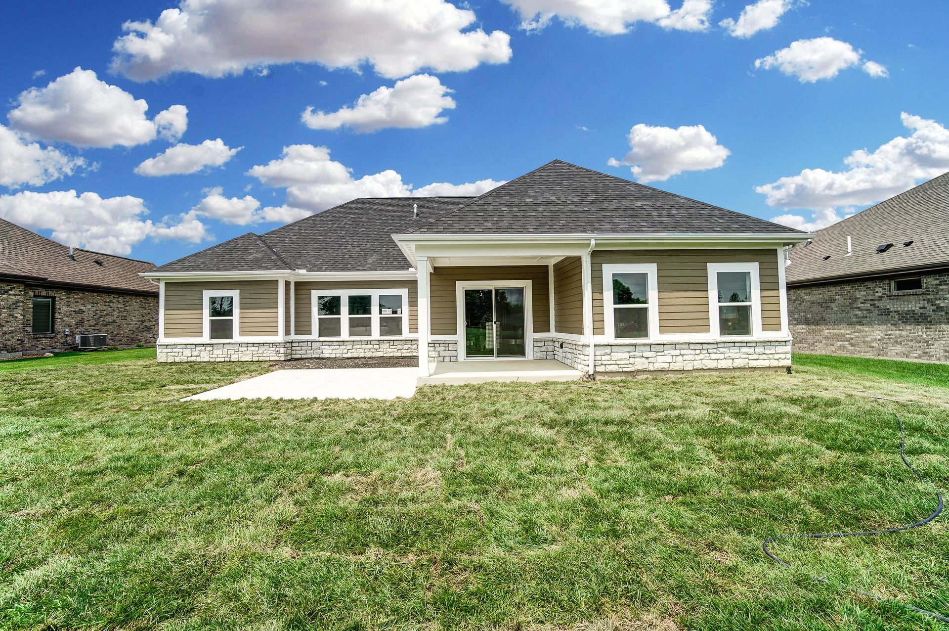The back of a house with a large lawn in front of it.