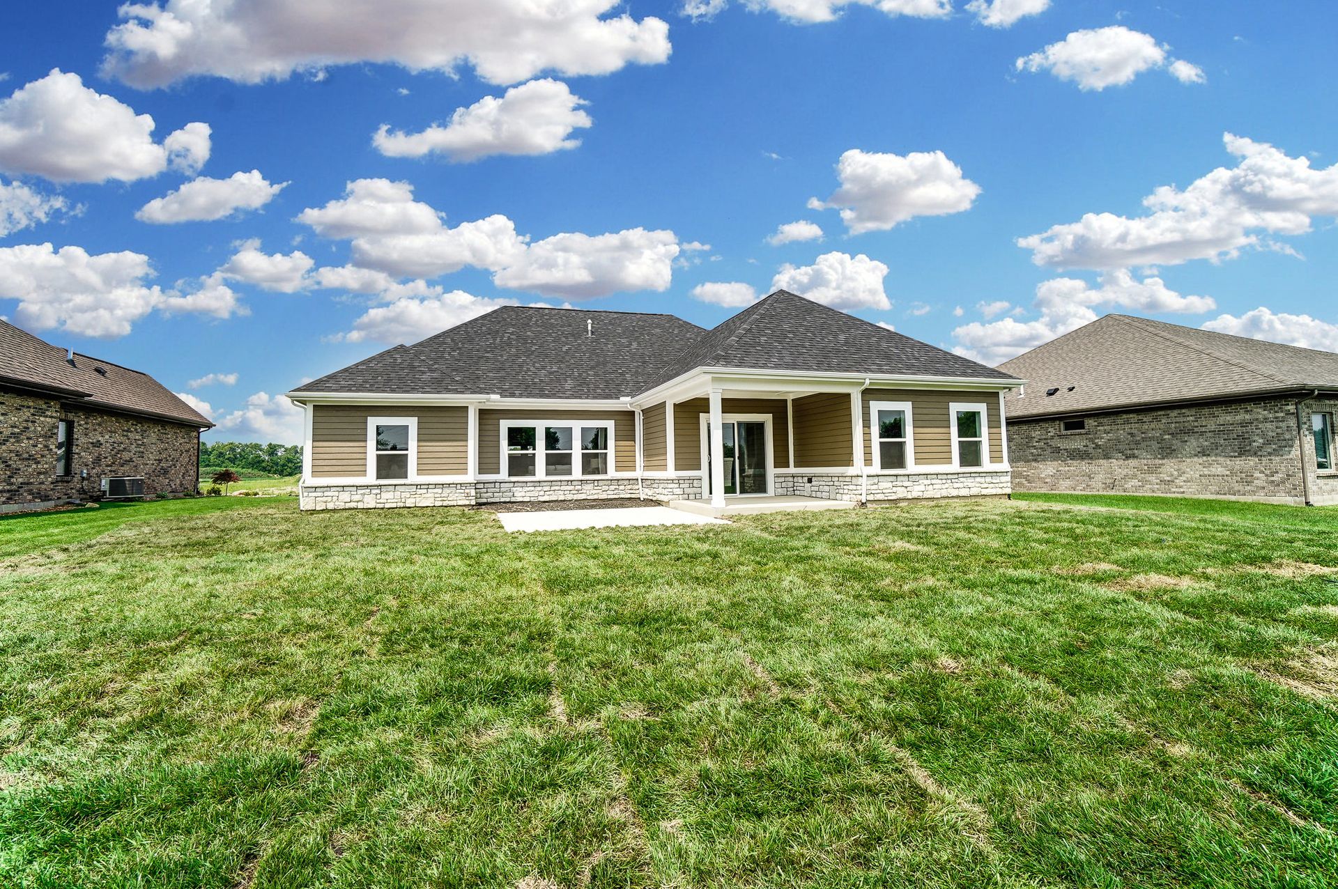 The back of a house with a large lawn in front of it.