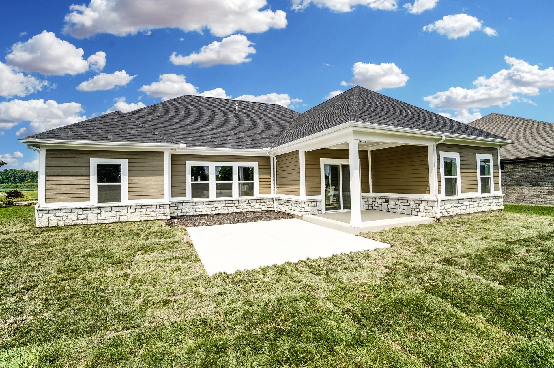 The back of a house with a large lawn in front of it.