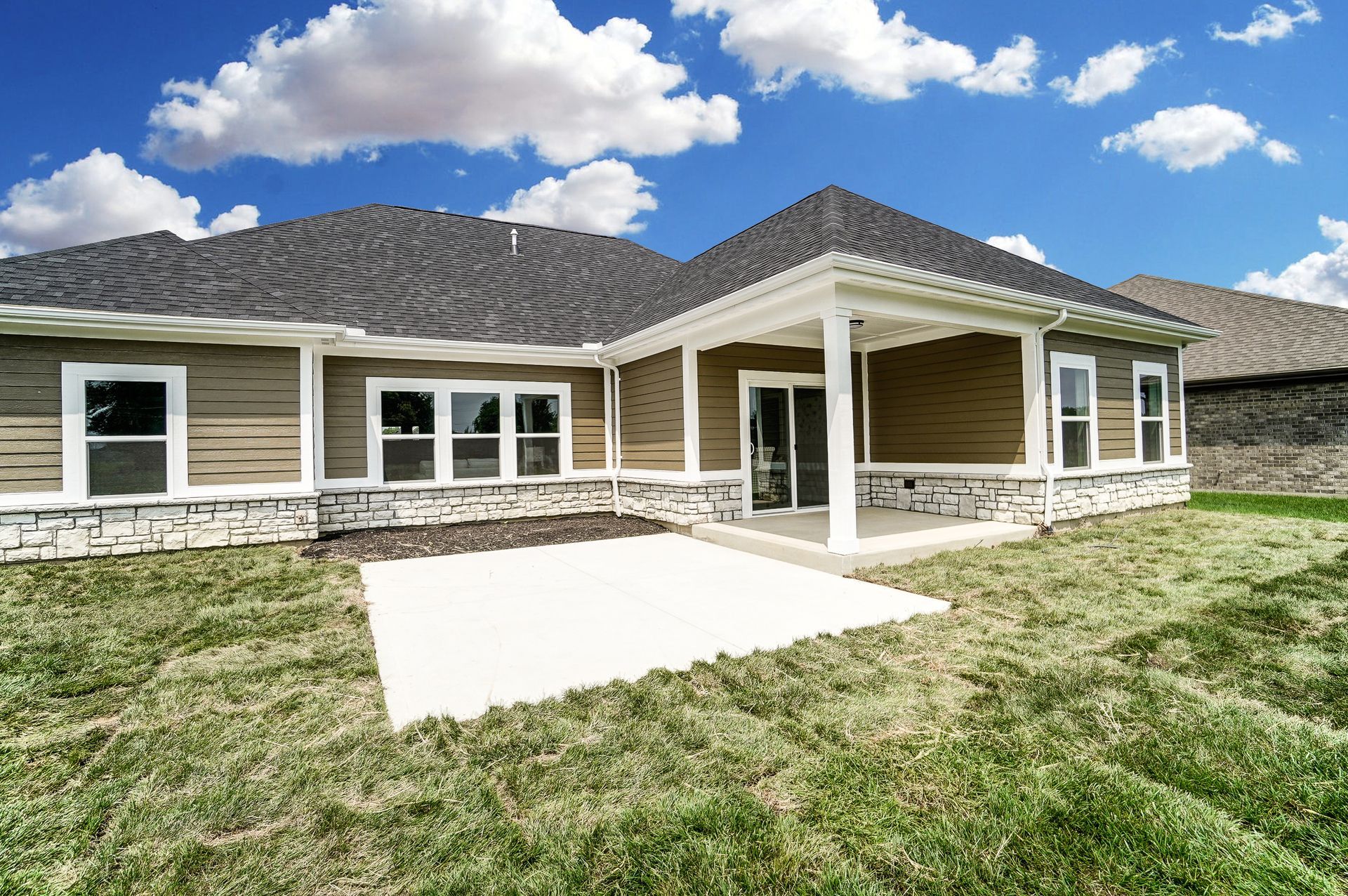 The back of a house with a porch and a lot of windows.