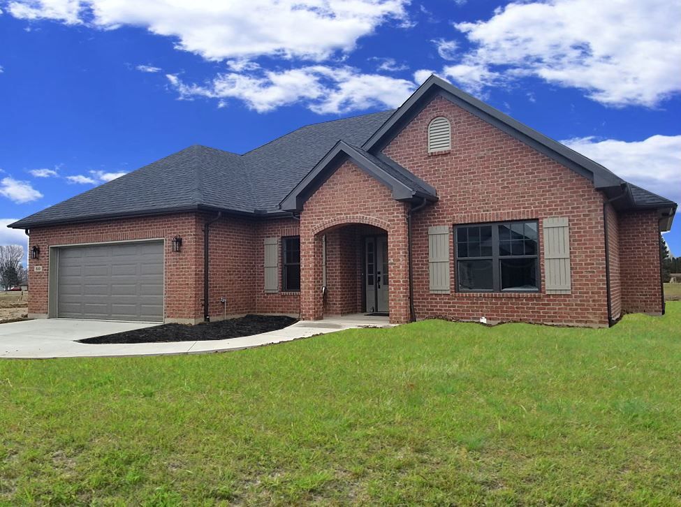 A brick house with a garage and a clock on the top of it