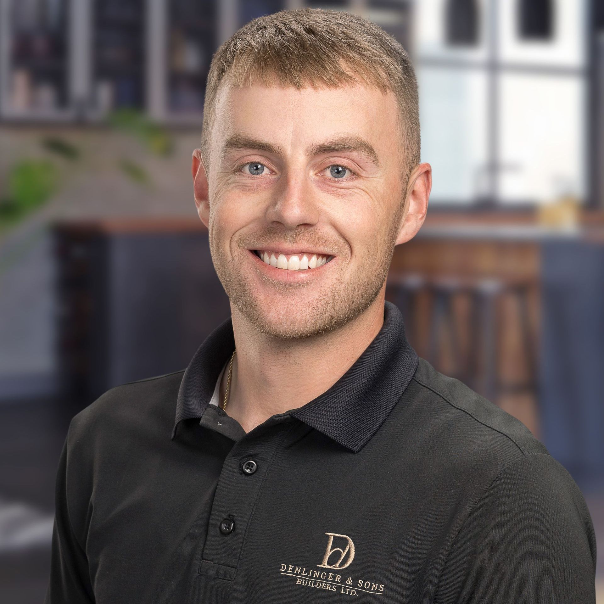 A man wearing a black polo shirt is smiling for the camera.