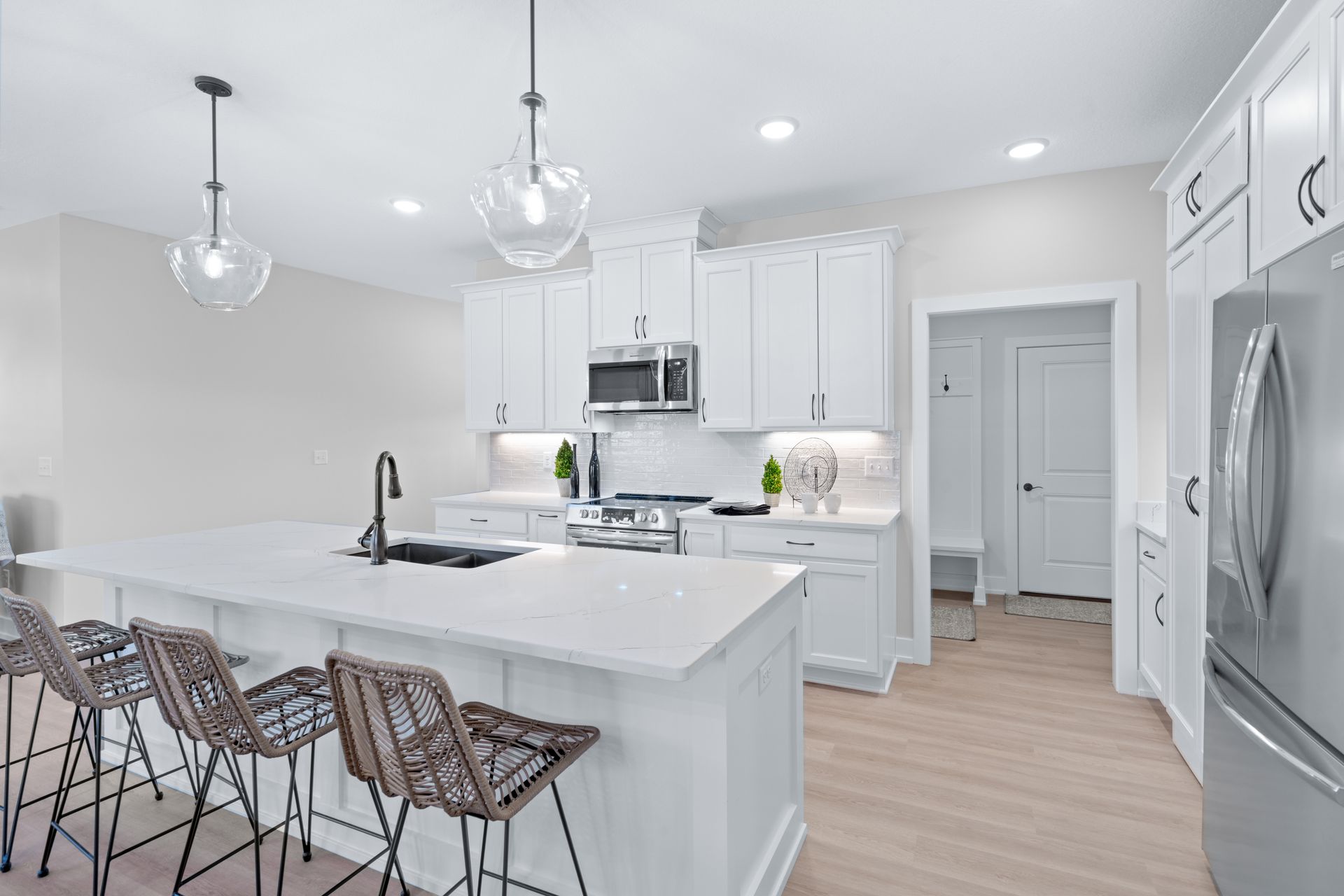 A kitchen with white cabinets , stainless steel appliances , and a large island.