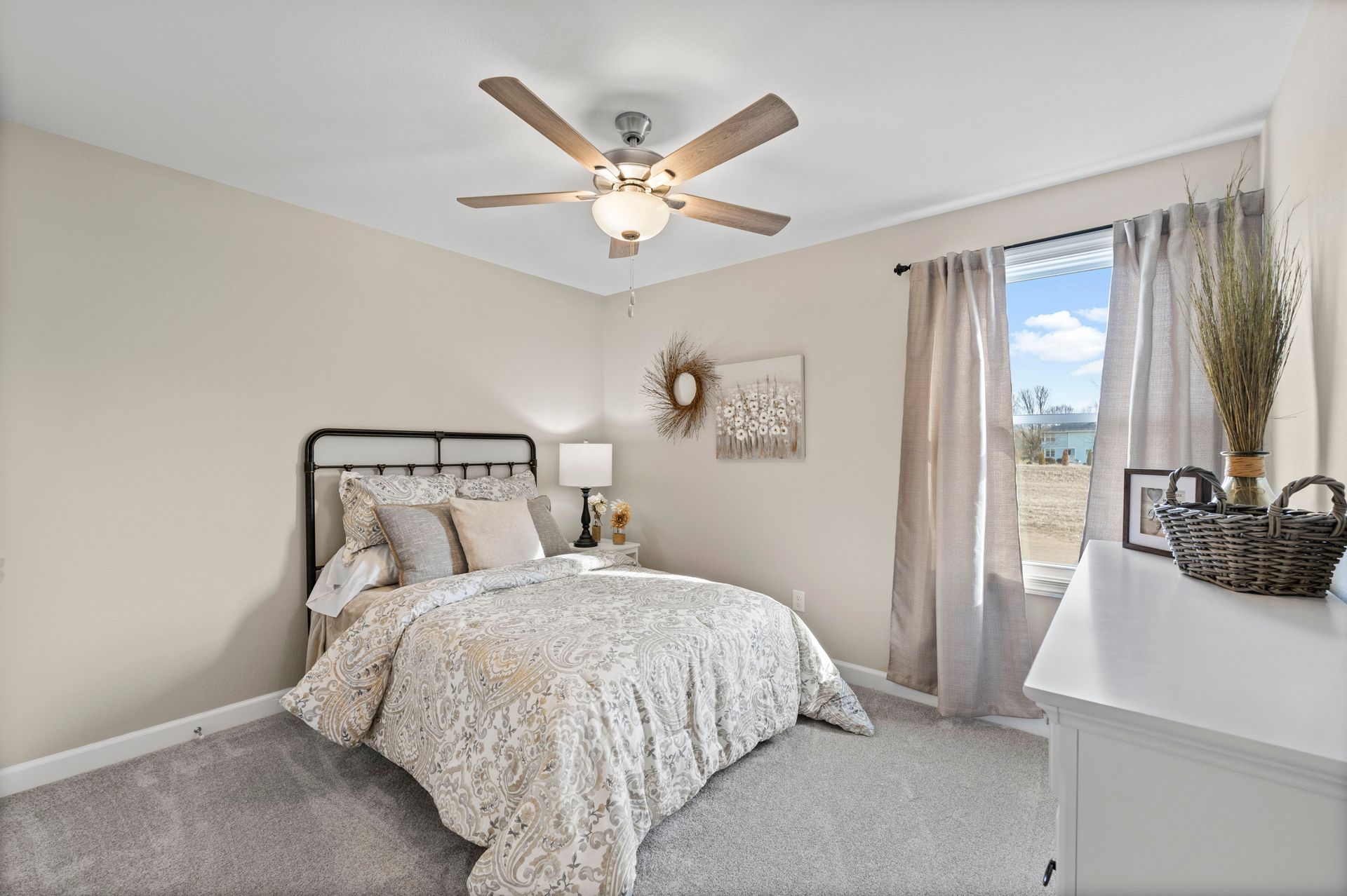 A bedroom with a bed , ceiling fan , dresser and window.
