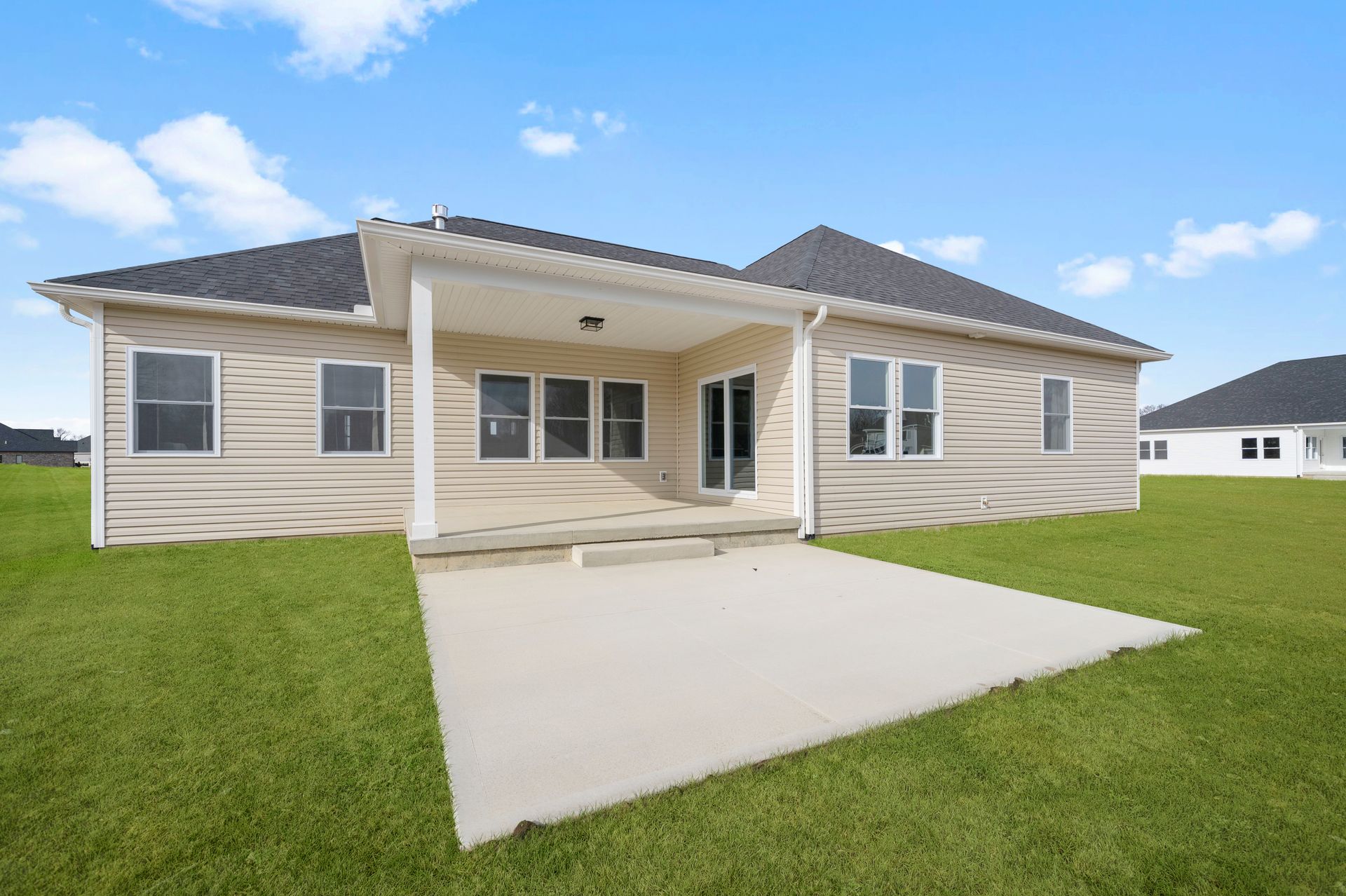 The back of a house with a concrete driveway in front of it.