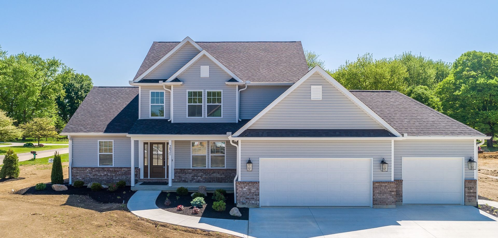 A large white house with a black roof and a large driveway.