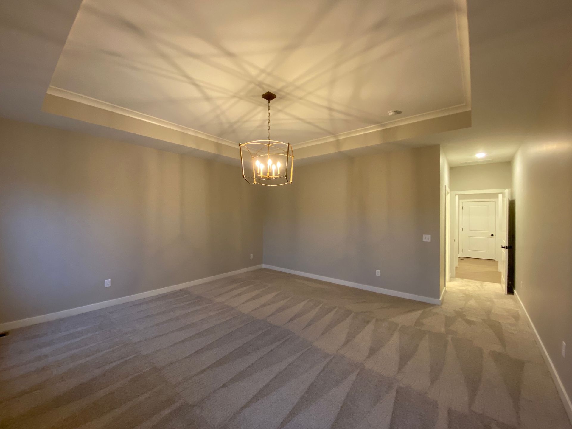 An empty room with a chandelier hanging from the ceiling.