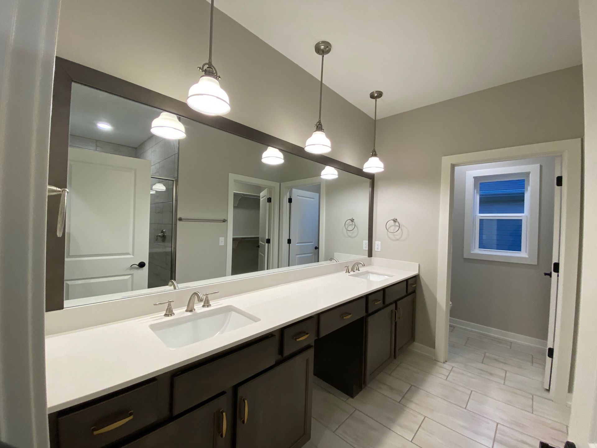 A bathroom with two sinks , two mirrors and a window.