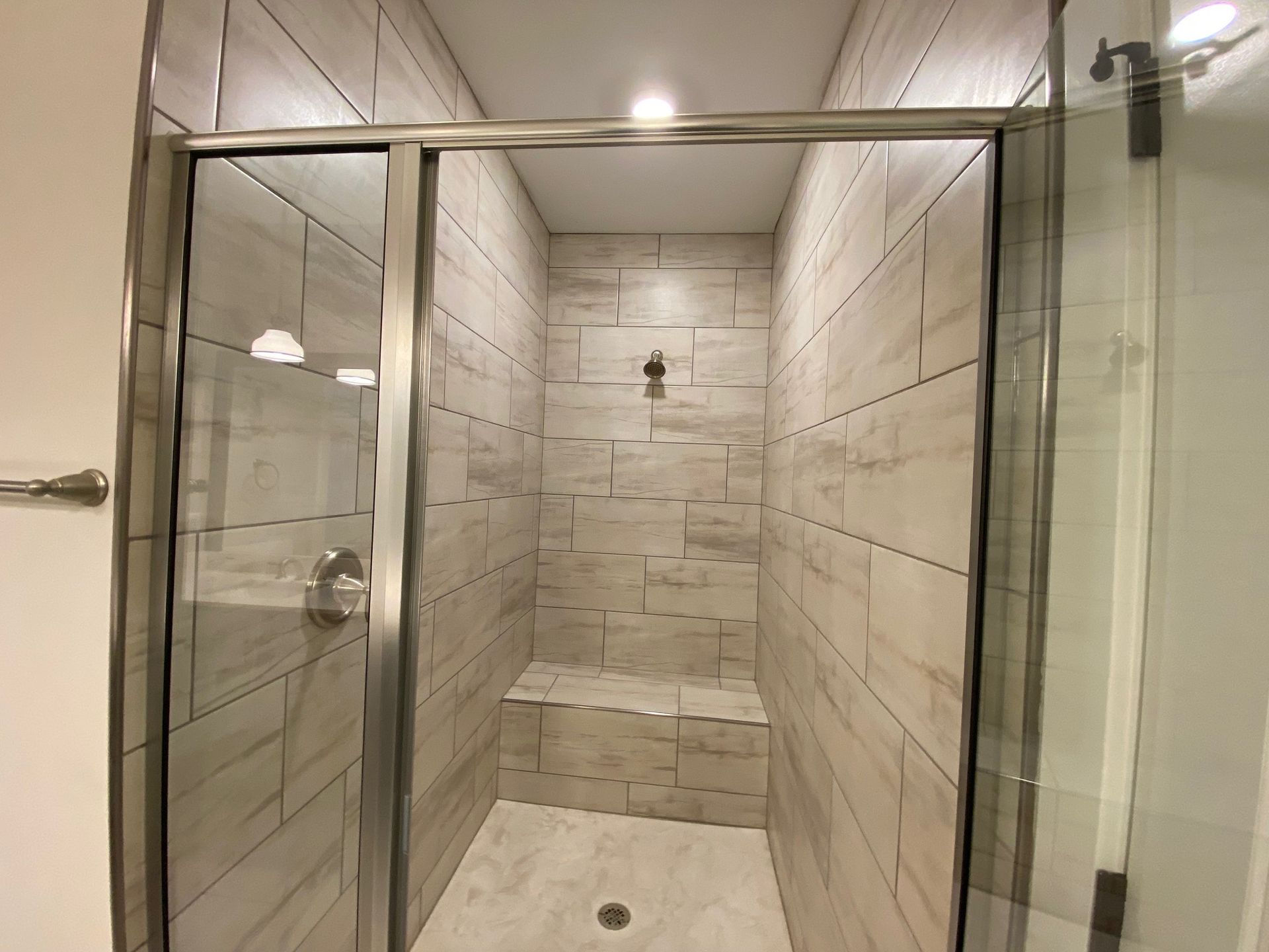 A bathroom with a walk in shower with a glass door