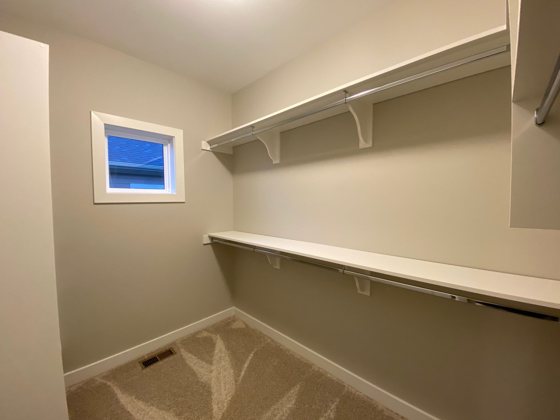 An empty walk in closet with shelves and a window.