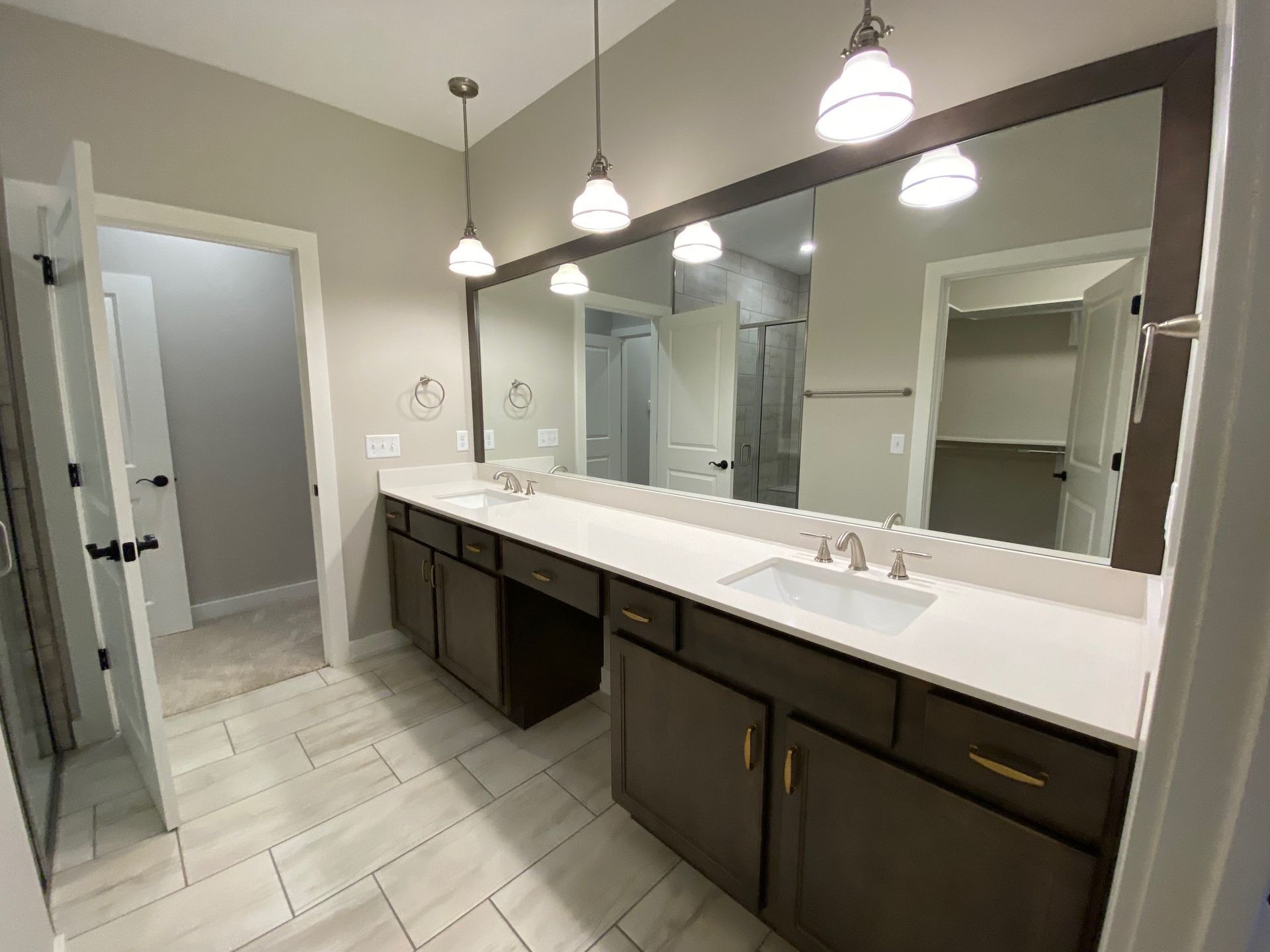A bathroom with two sinks , two mirrors , and a walk in closet.