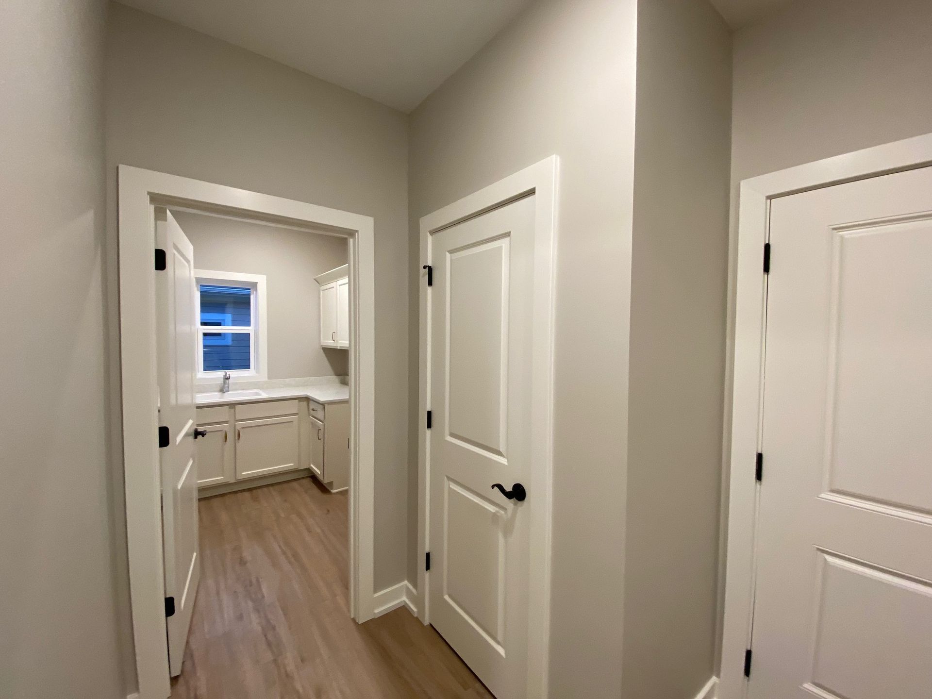 A hallway leading to a laundry room in a house.