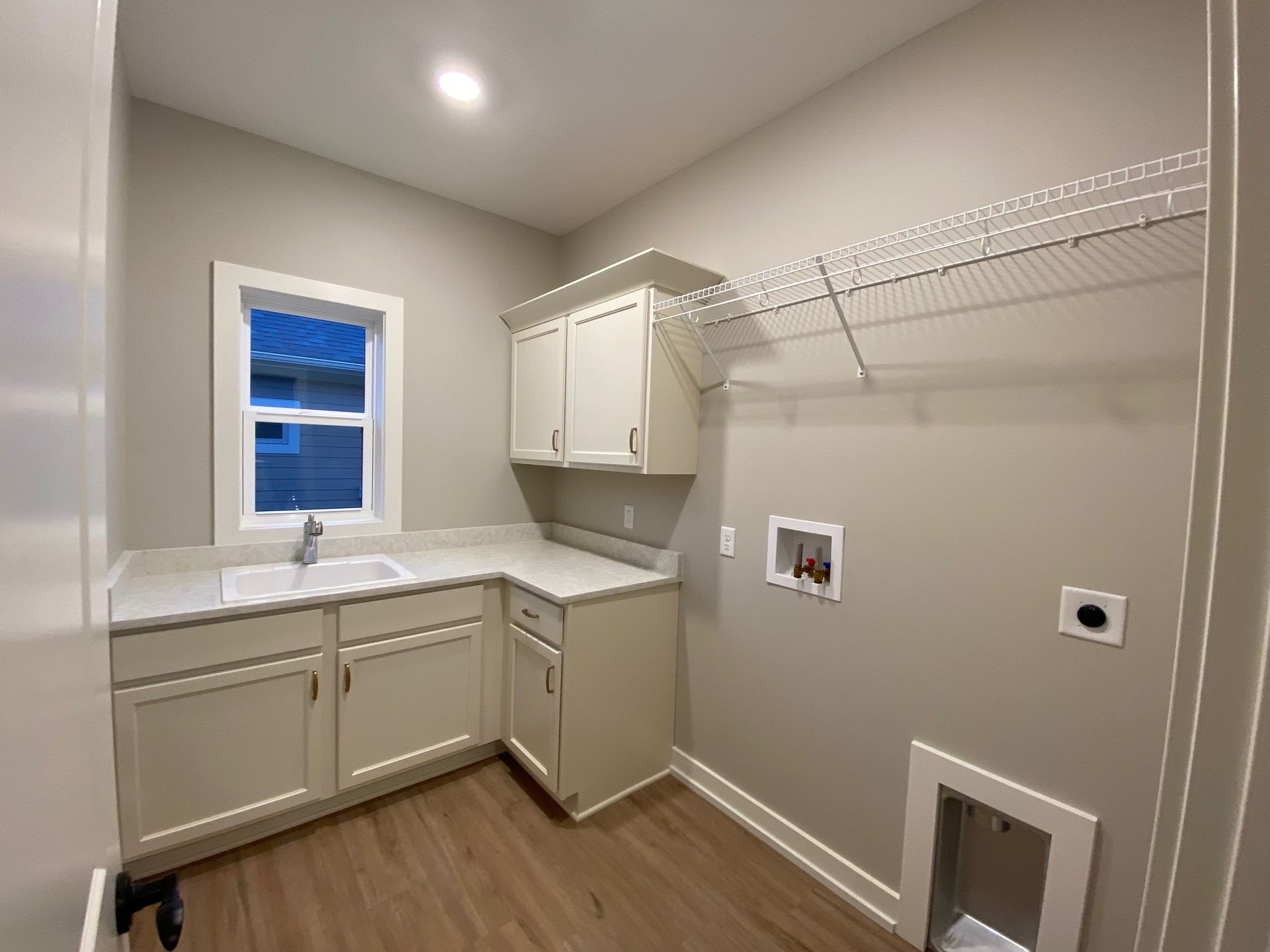 A laundry room with a sink , cabinets , and a window.