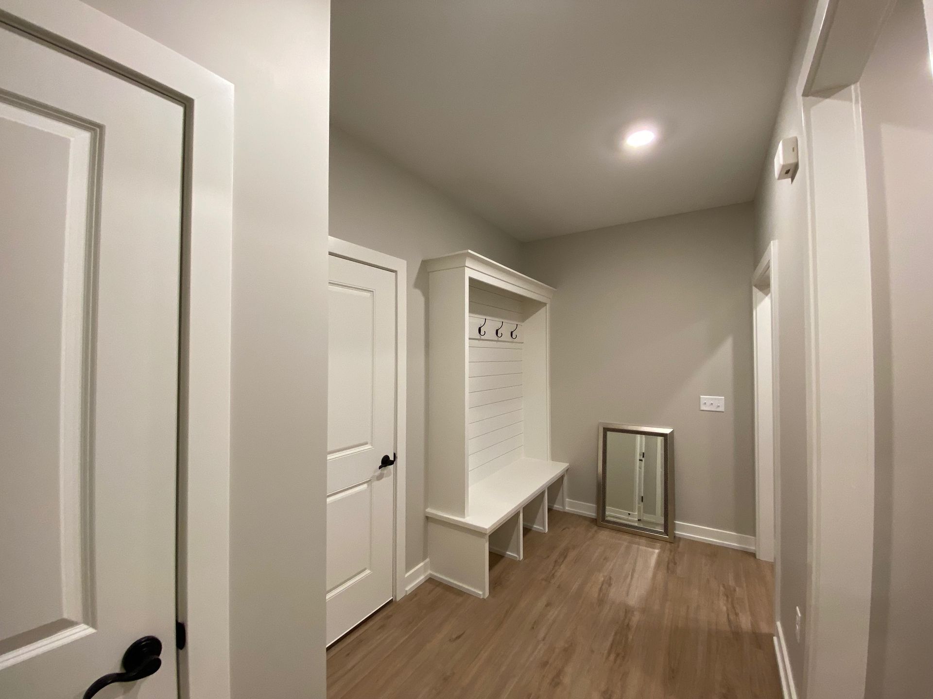 A hallway with a bench and a mirror in a house.