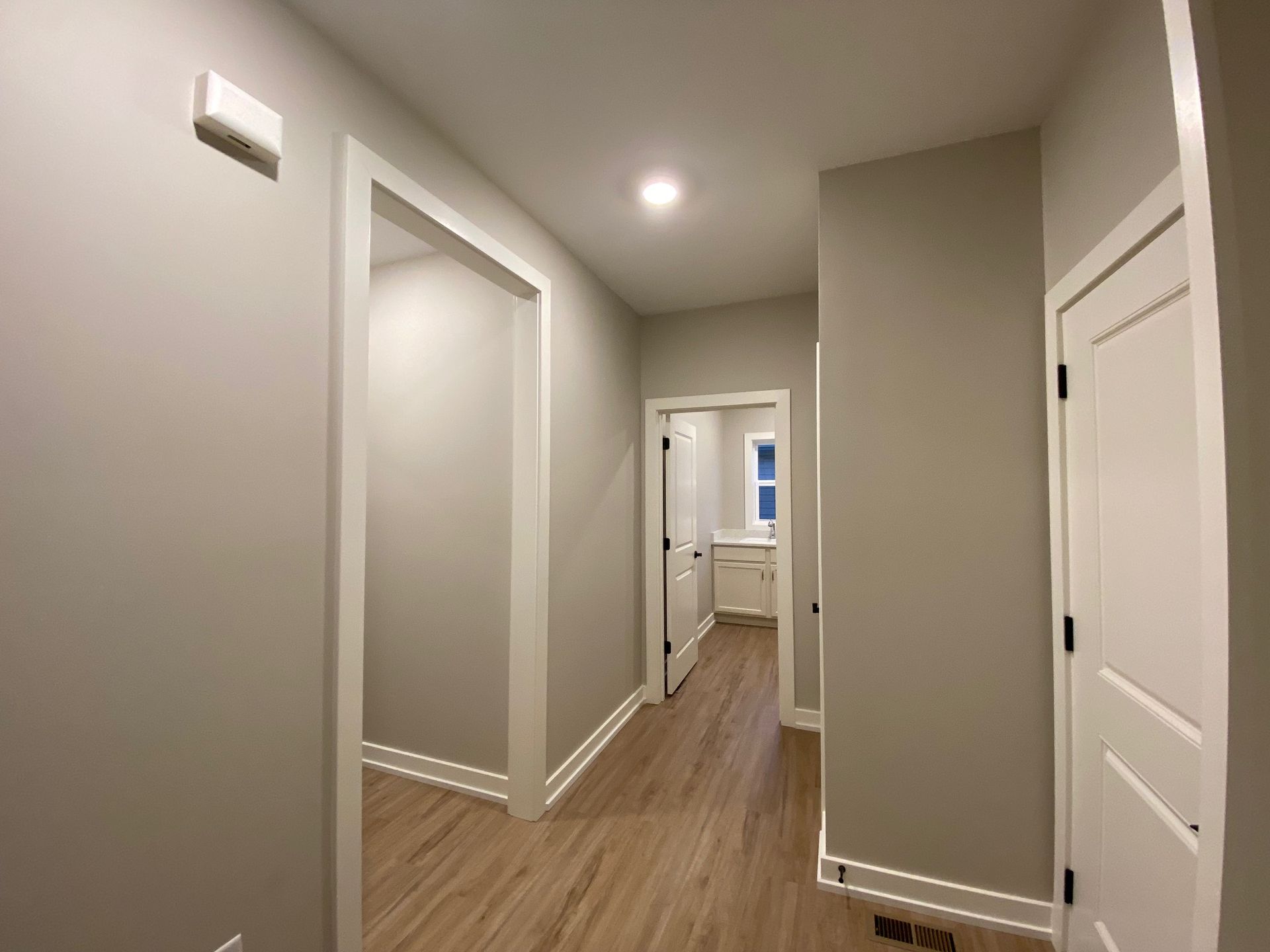 A hallway in a house with wooden floors and gray walls.