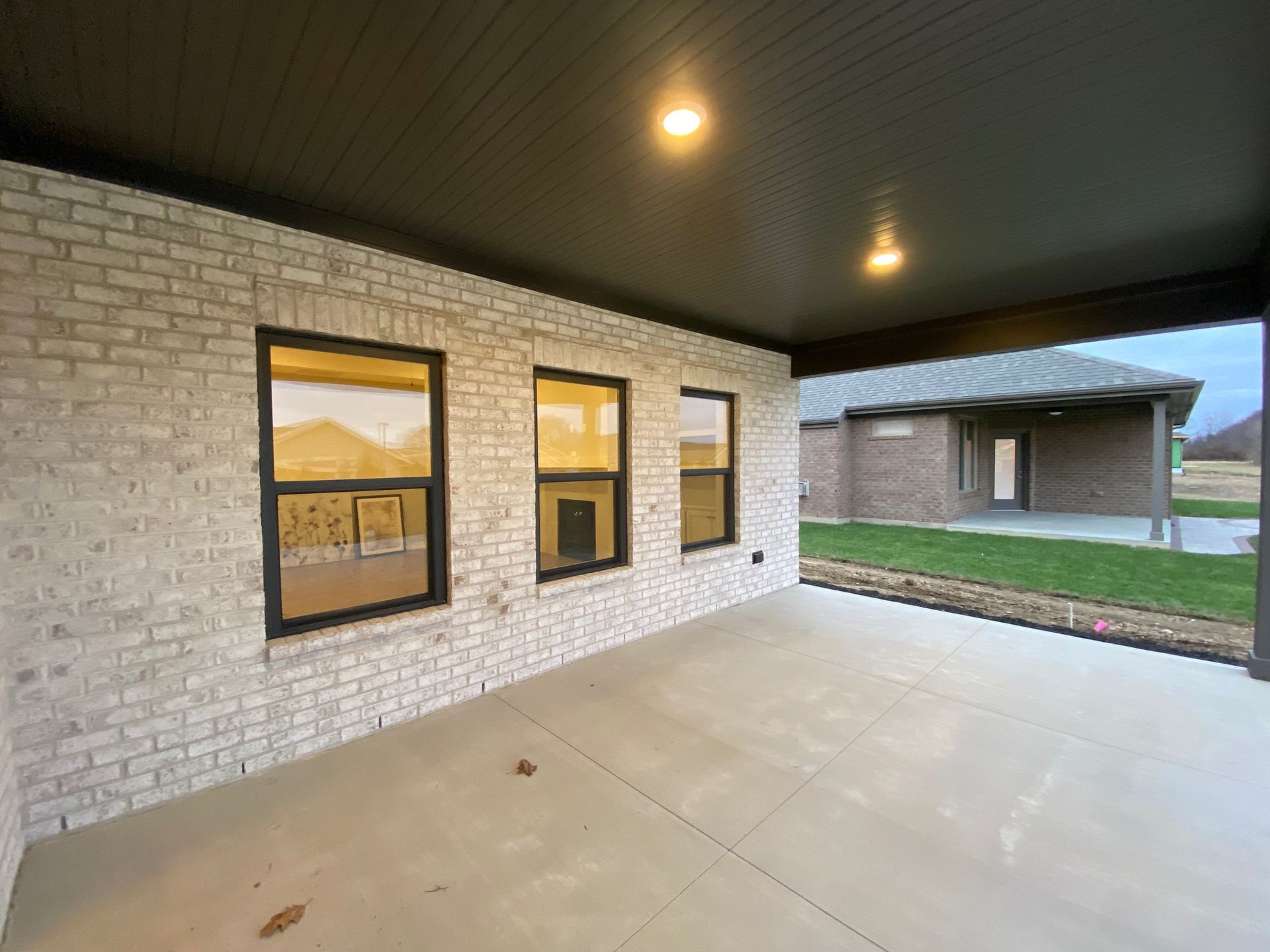 A large covered patio with a brick wall and windows in front of a house.