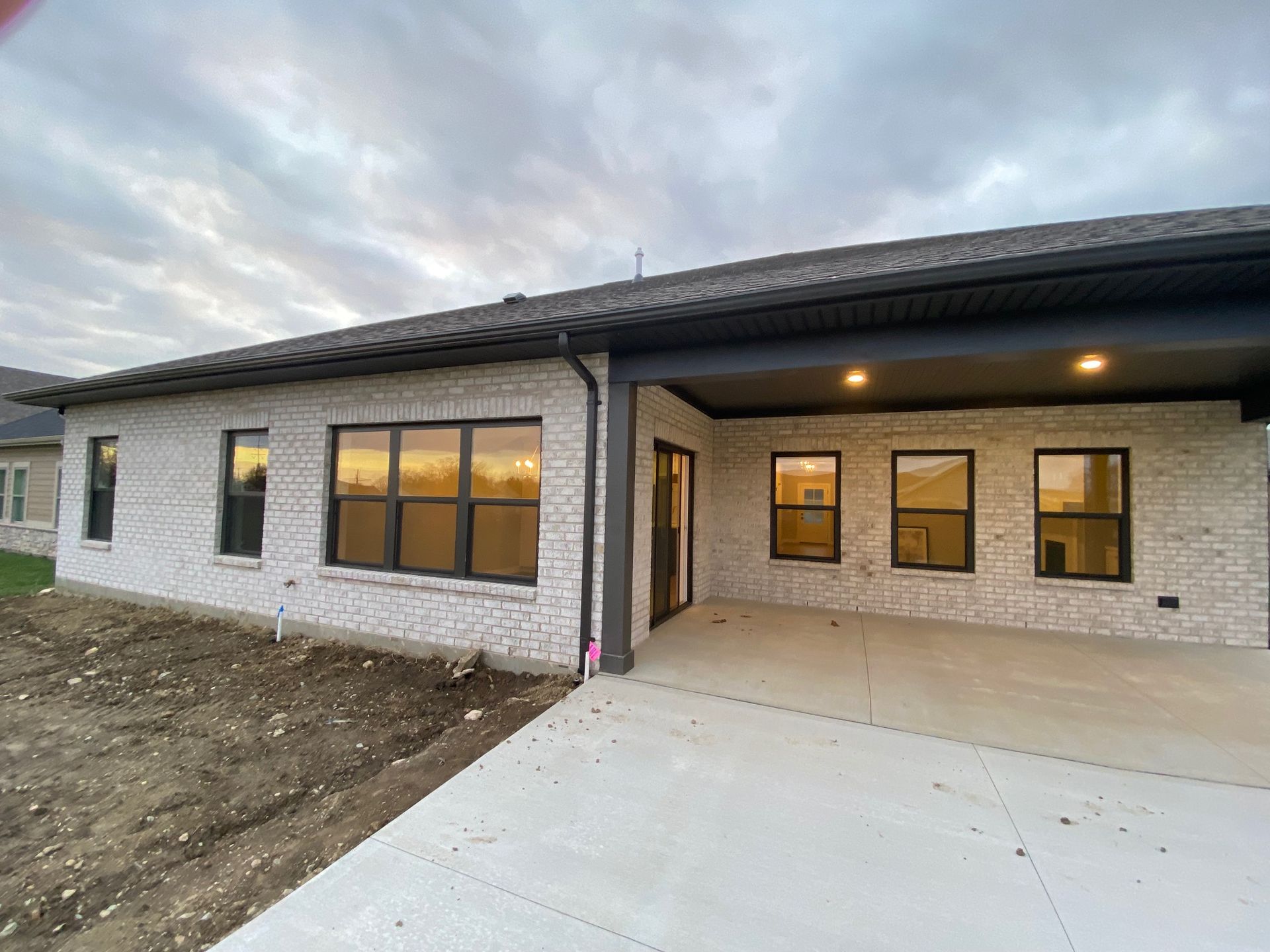 A white brick house with a lot of windows and a covered porch.