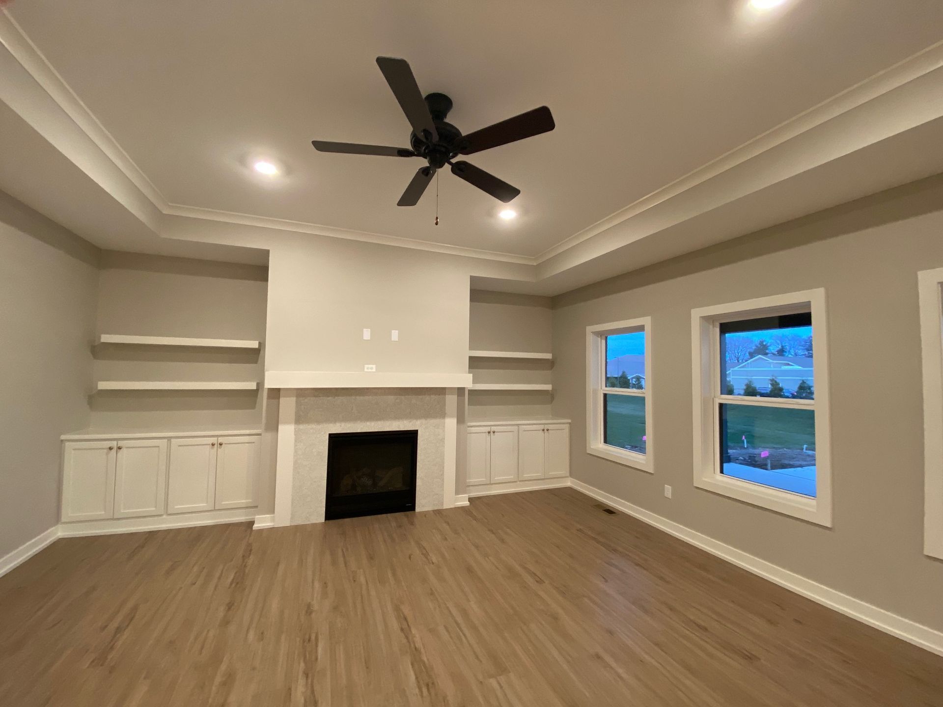An empty living room with a fireplace and a ceiling fan.