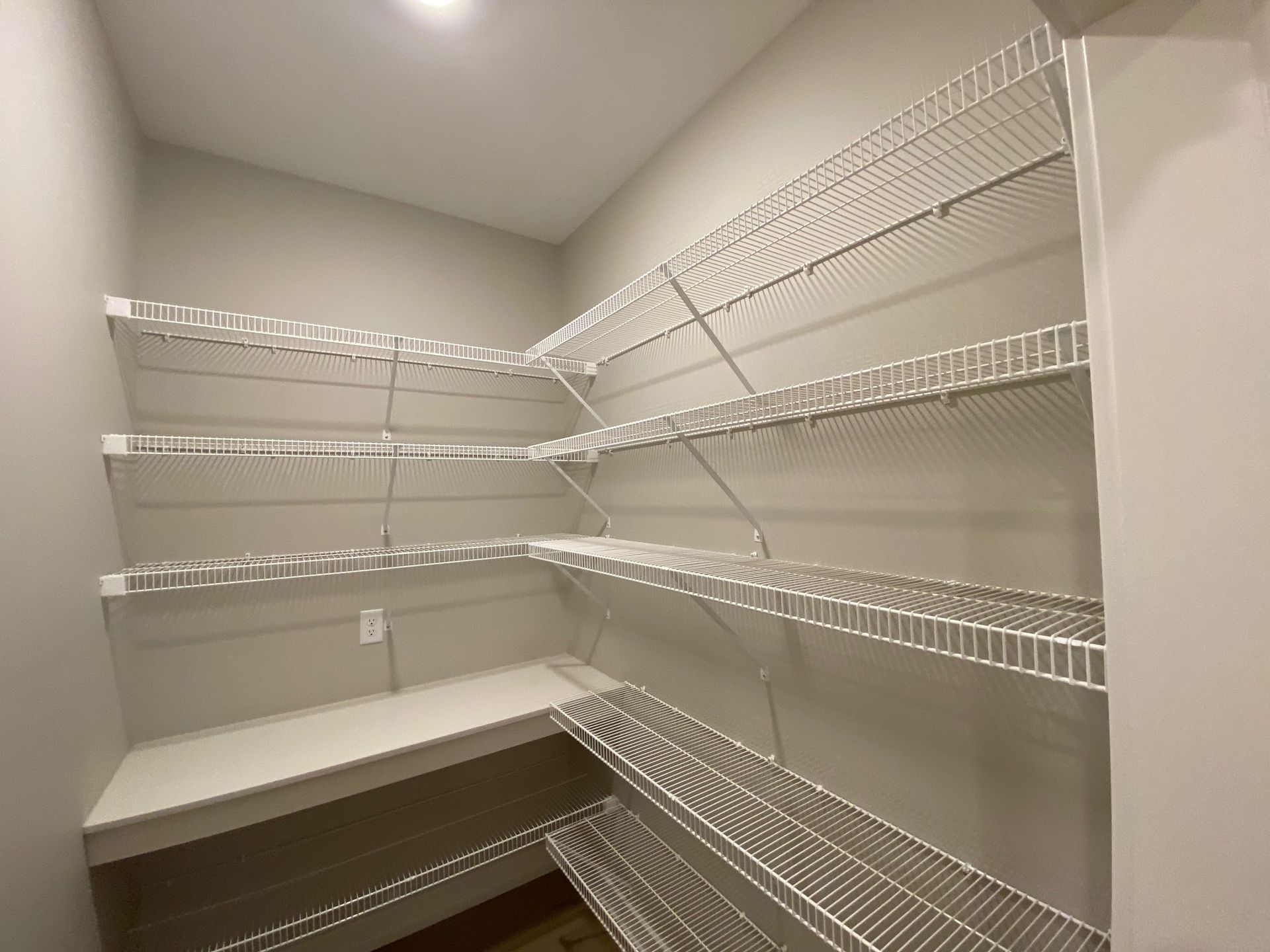 A walk in pantry with lots of shelves and a table.