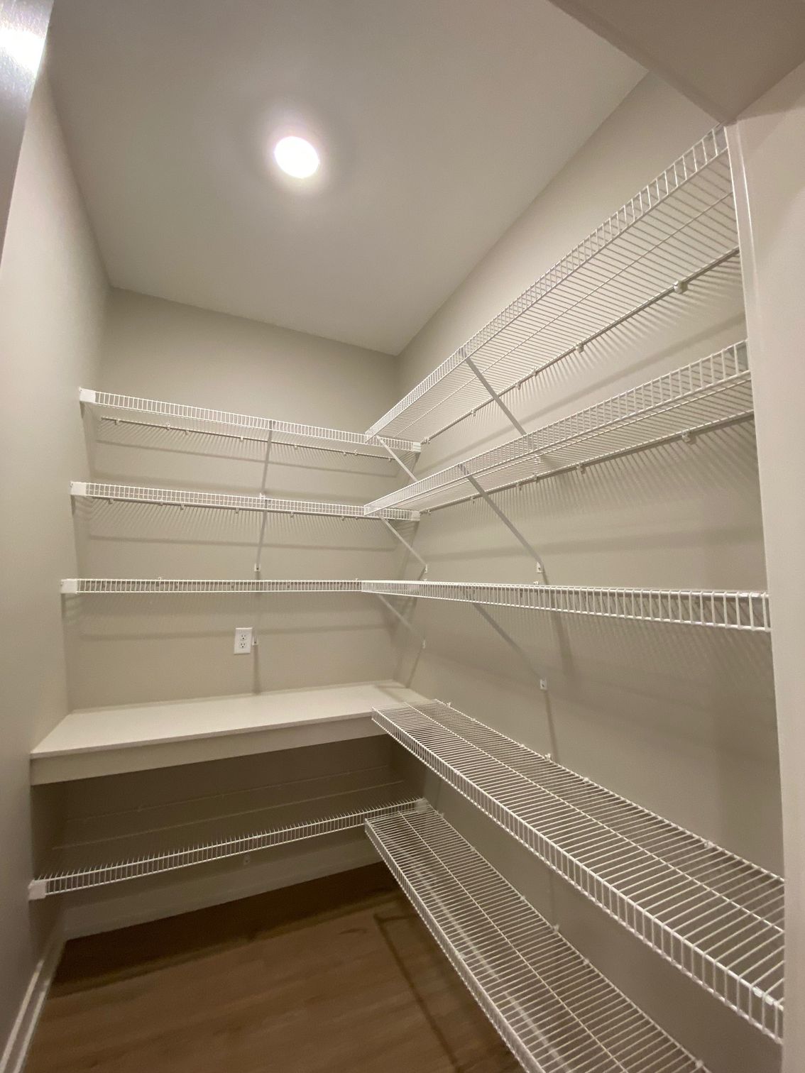 A walk in closet with lots of shelves and a table.