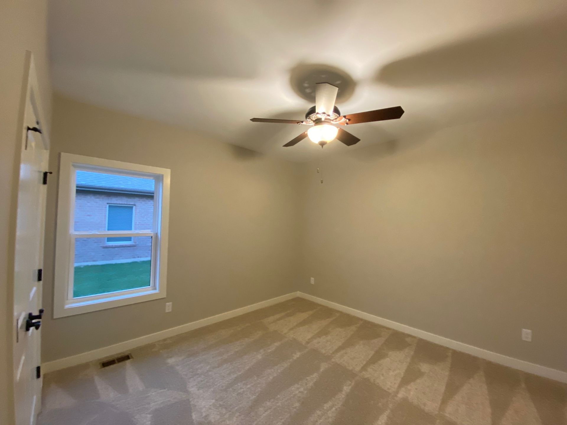 An empty bedroom with a ceiling fan and a window.
