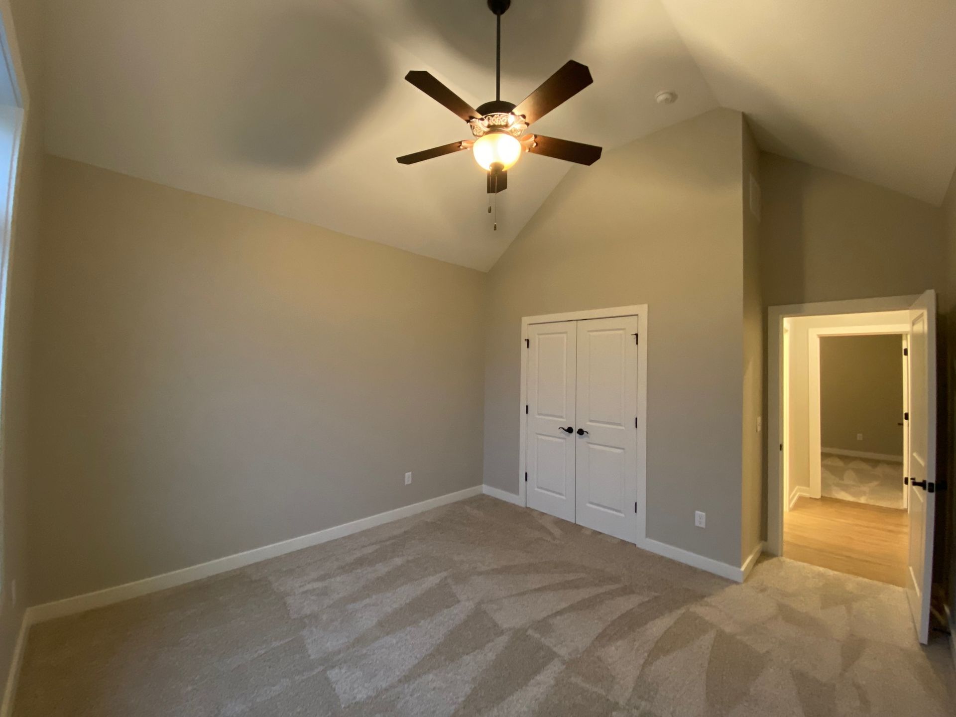 An empty bedroom with a ceiling fan and a closet.