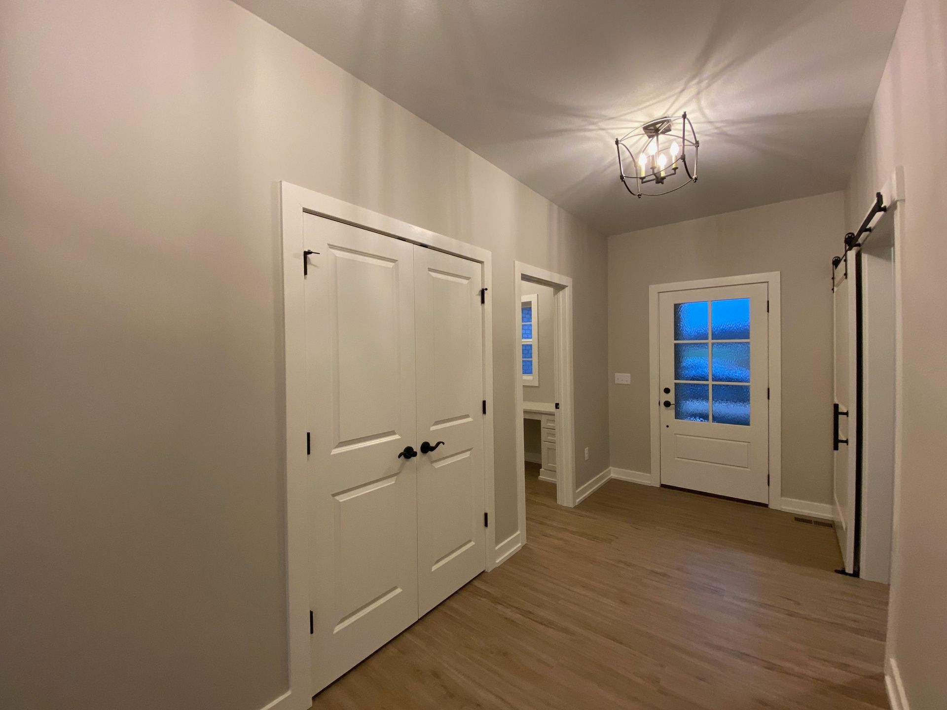 A hallway with hardwood floors and white doors in a house.