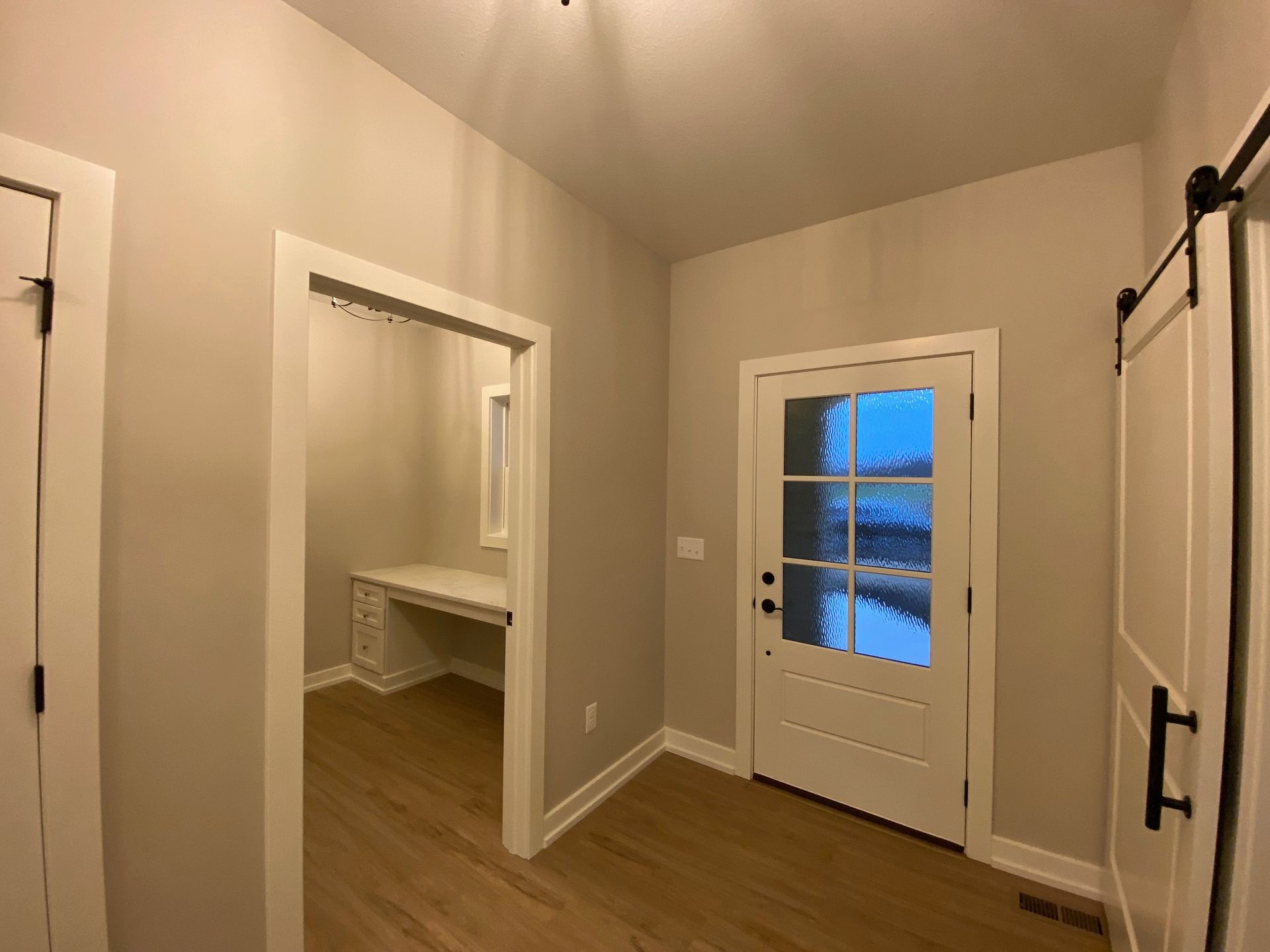 A hallway with a door and a desk in a house.