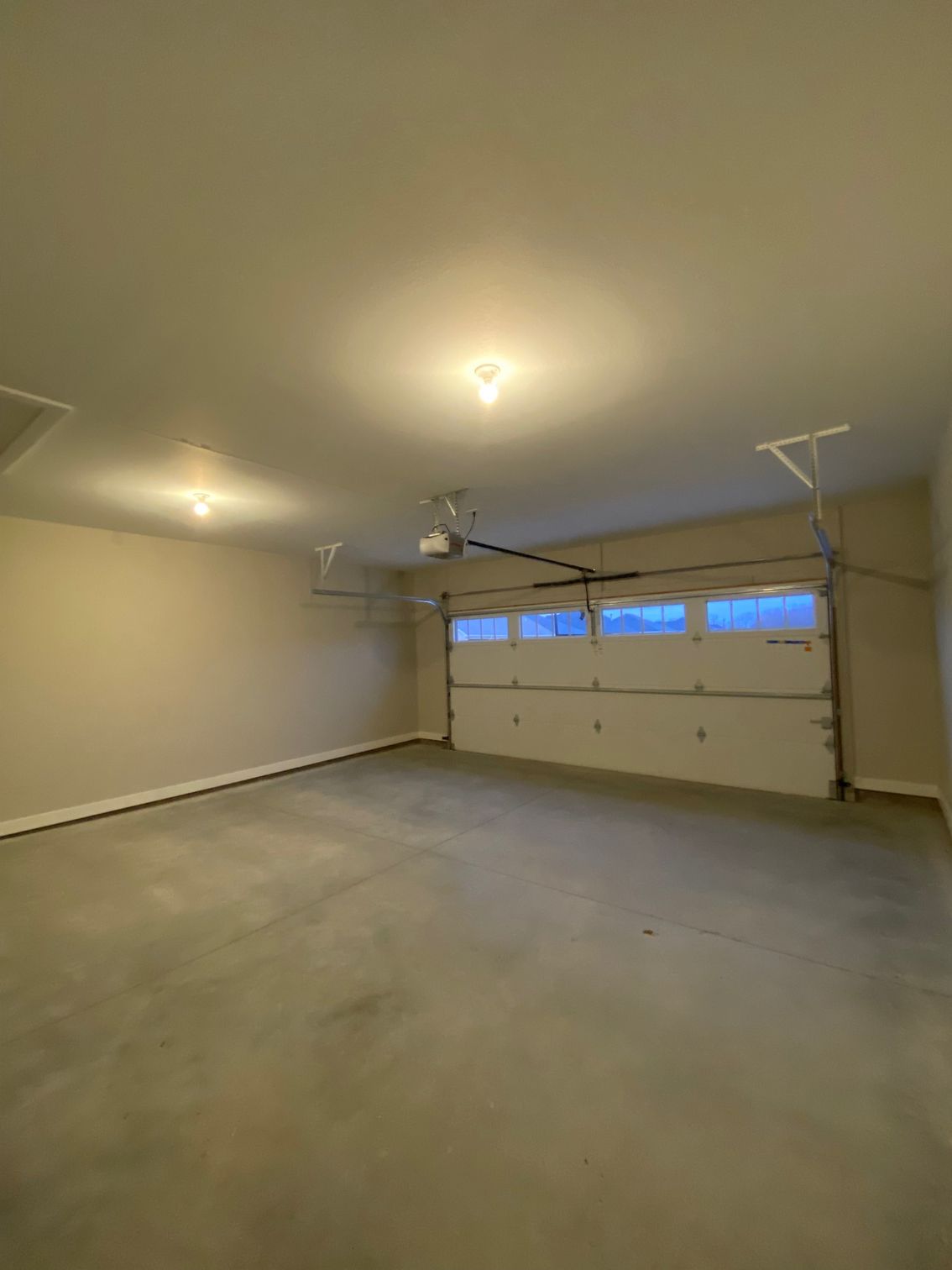 An empty garage with a garage door open and a ceiling fan.
