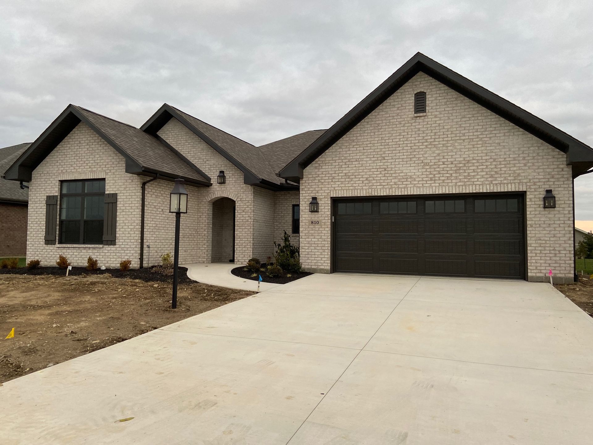 A large brick house with two garage doors and a concrete driveway.