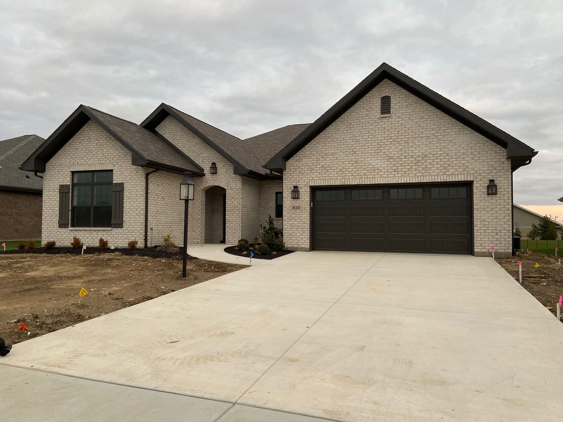 A large brick house with a black garage door and a concrete driveway.